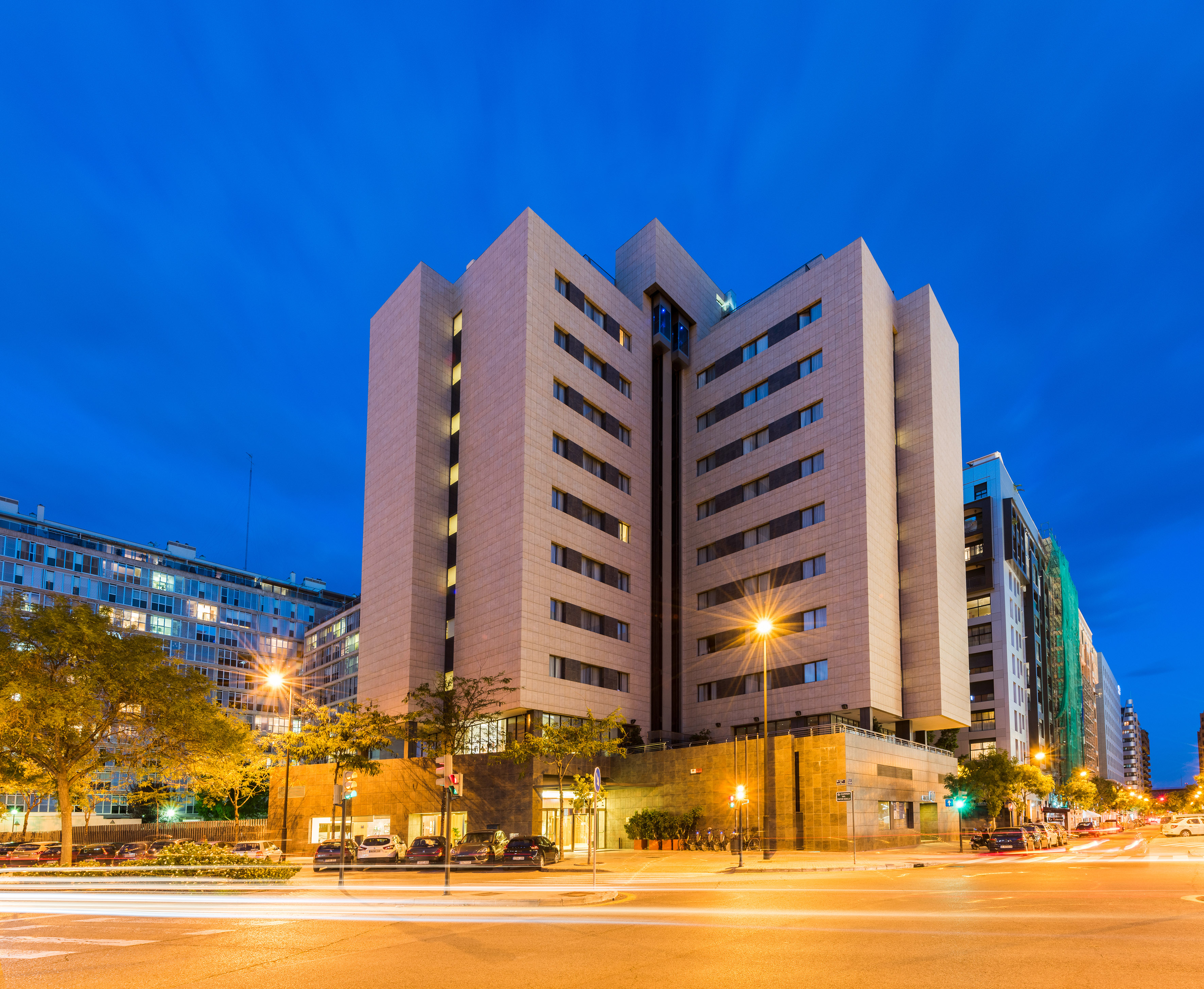 Modern city building at twilight with streetlights and car light trails.