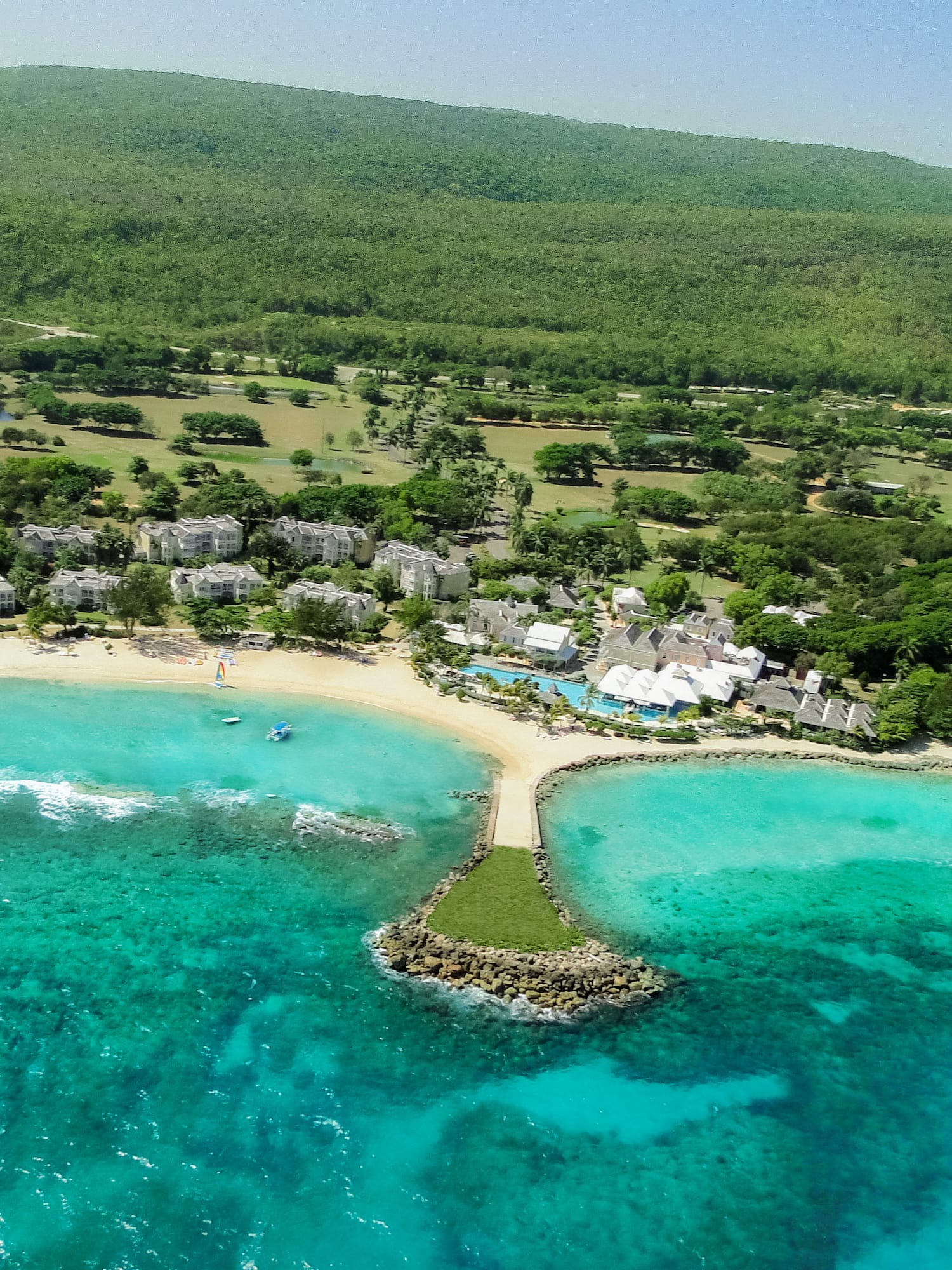 a beach with buildings and trees and blue water