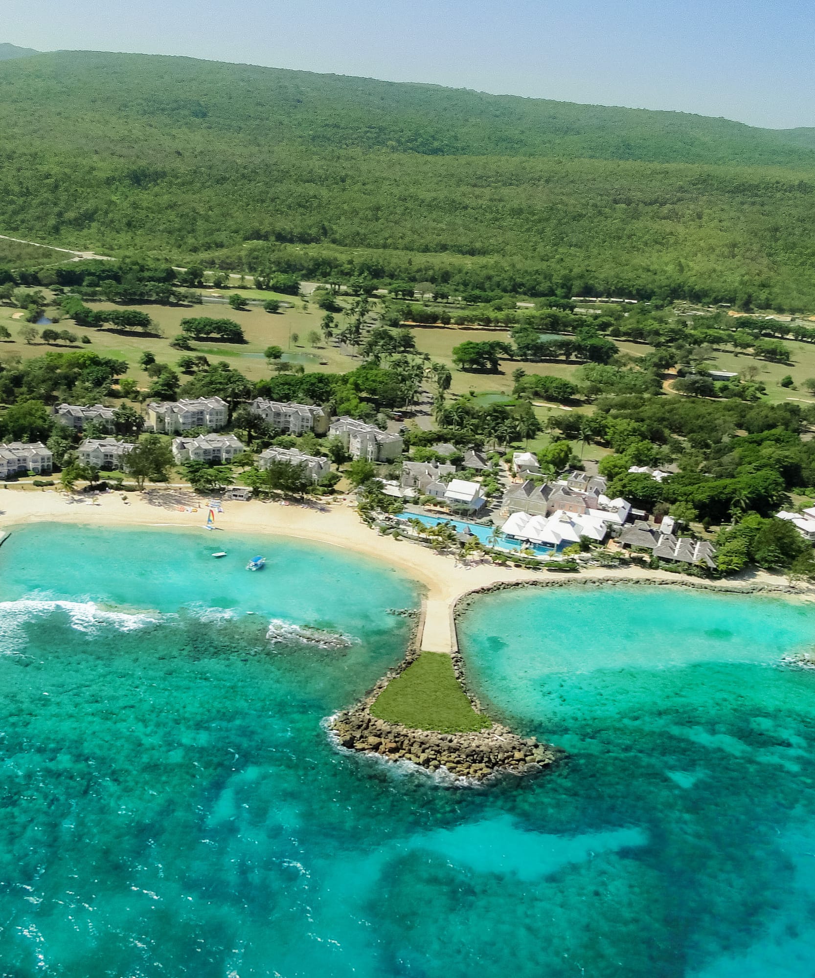 a beach with buildings and trees and blue water