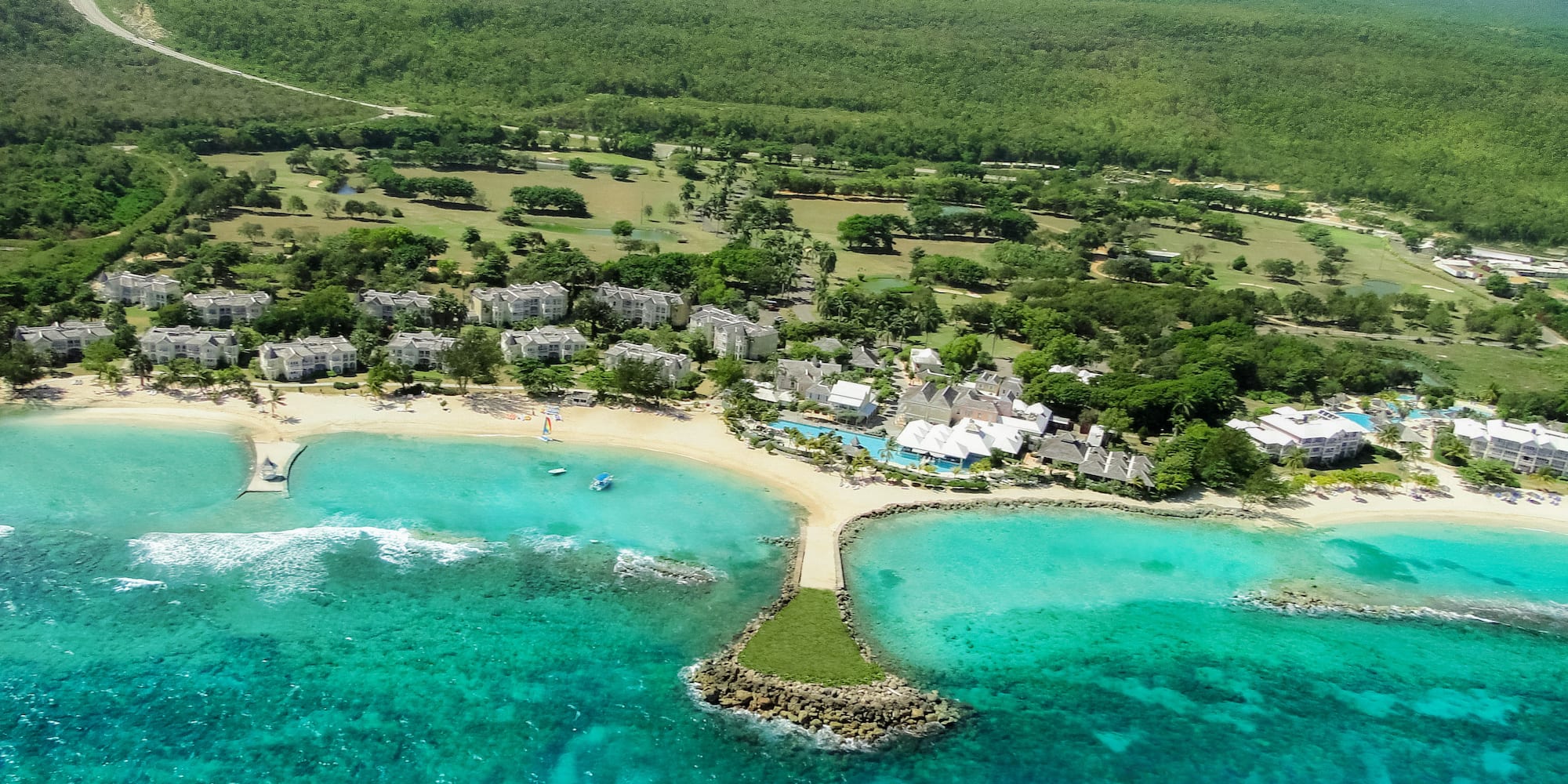 a beach with buildings and trees and blue water