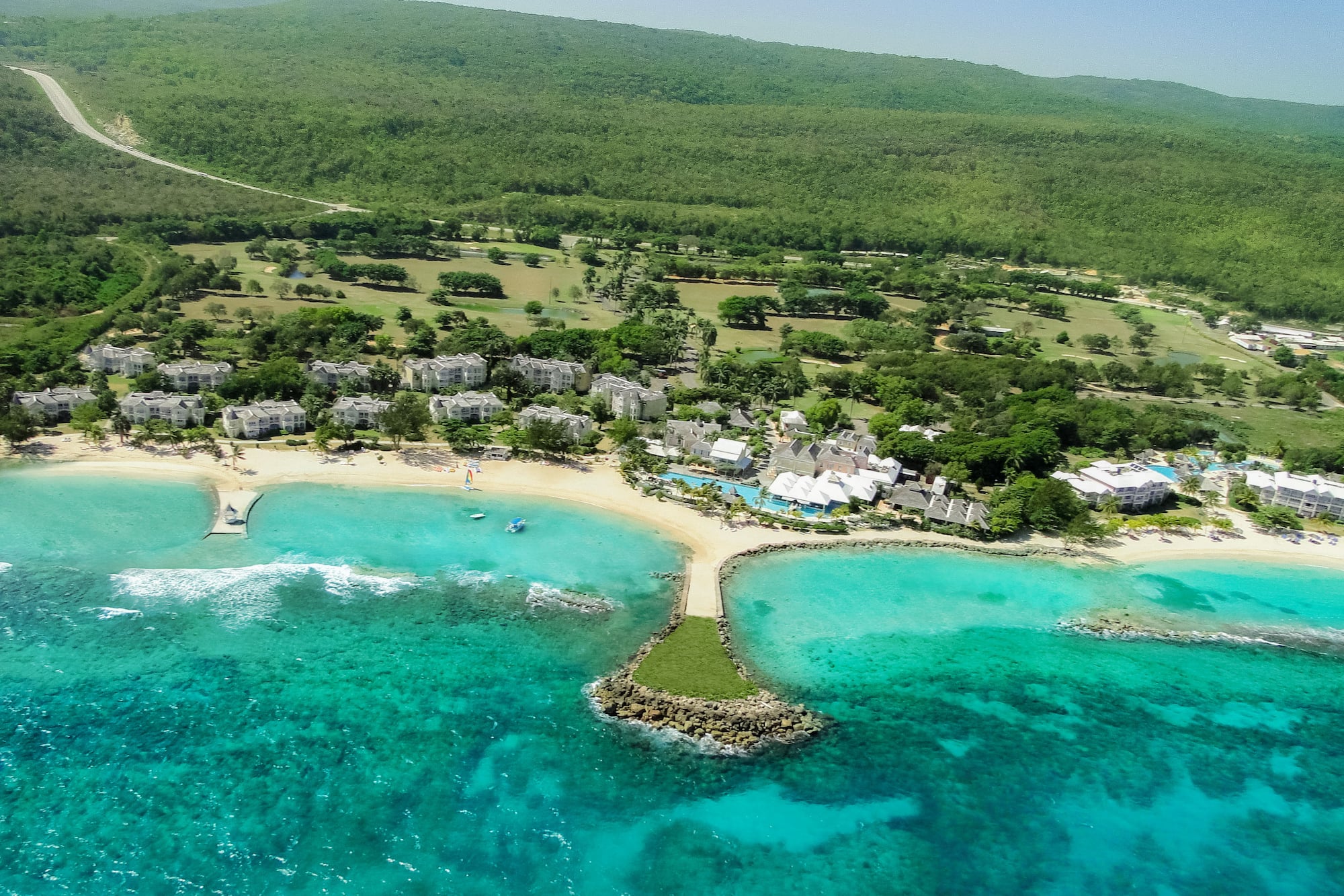 a beach with buildings and trees and blue water