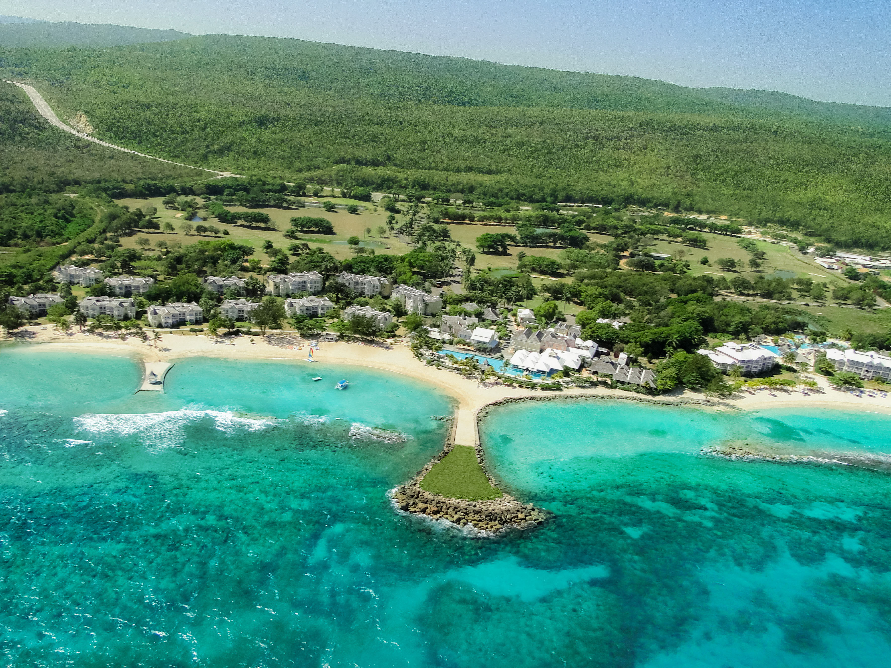 a beach with buildings and trees and blue water