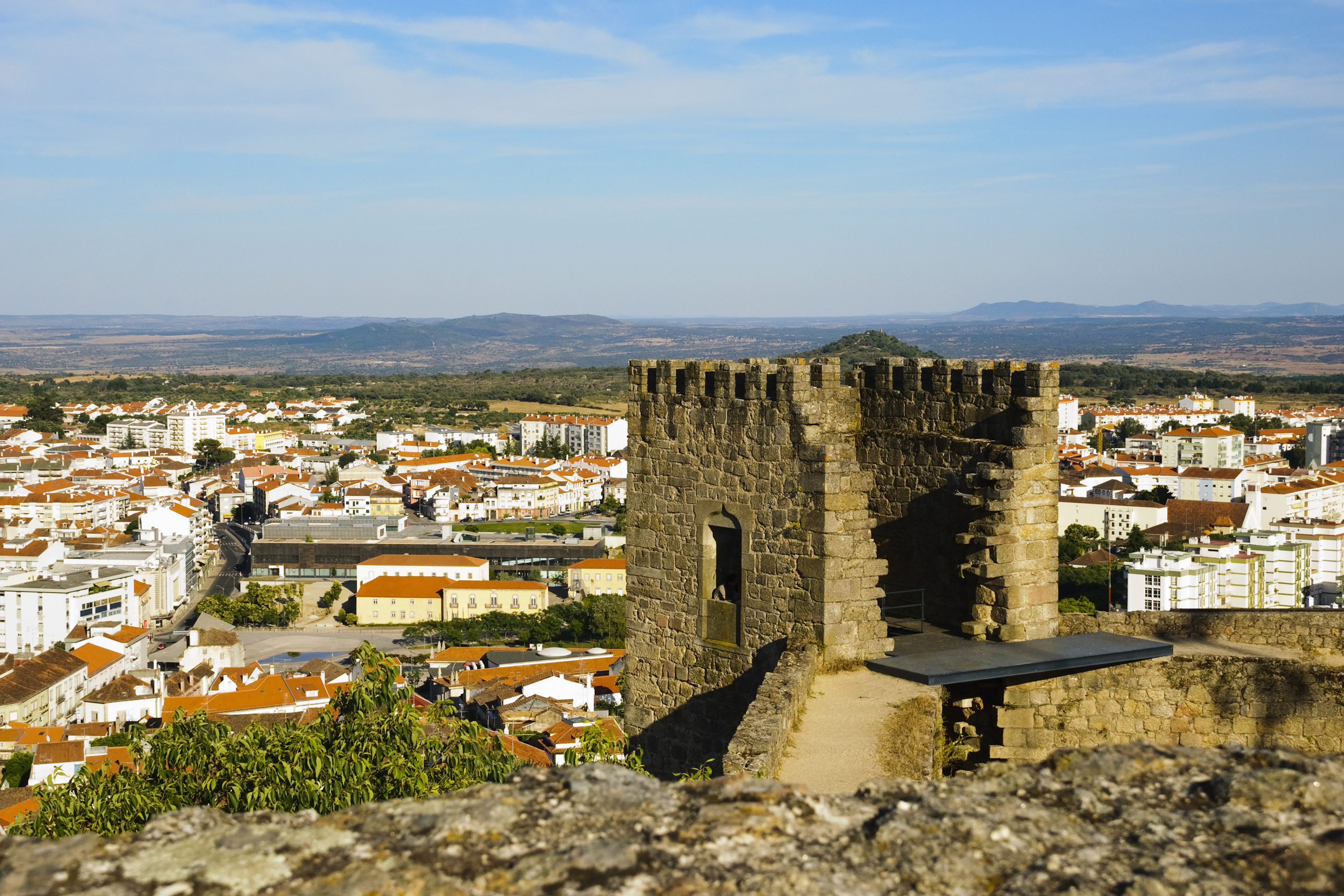Ancient castle tower overlooking a historic town and vast landscape.
