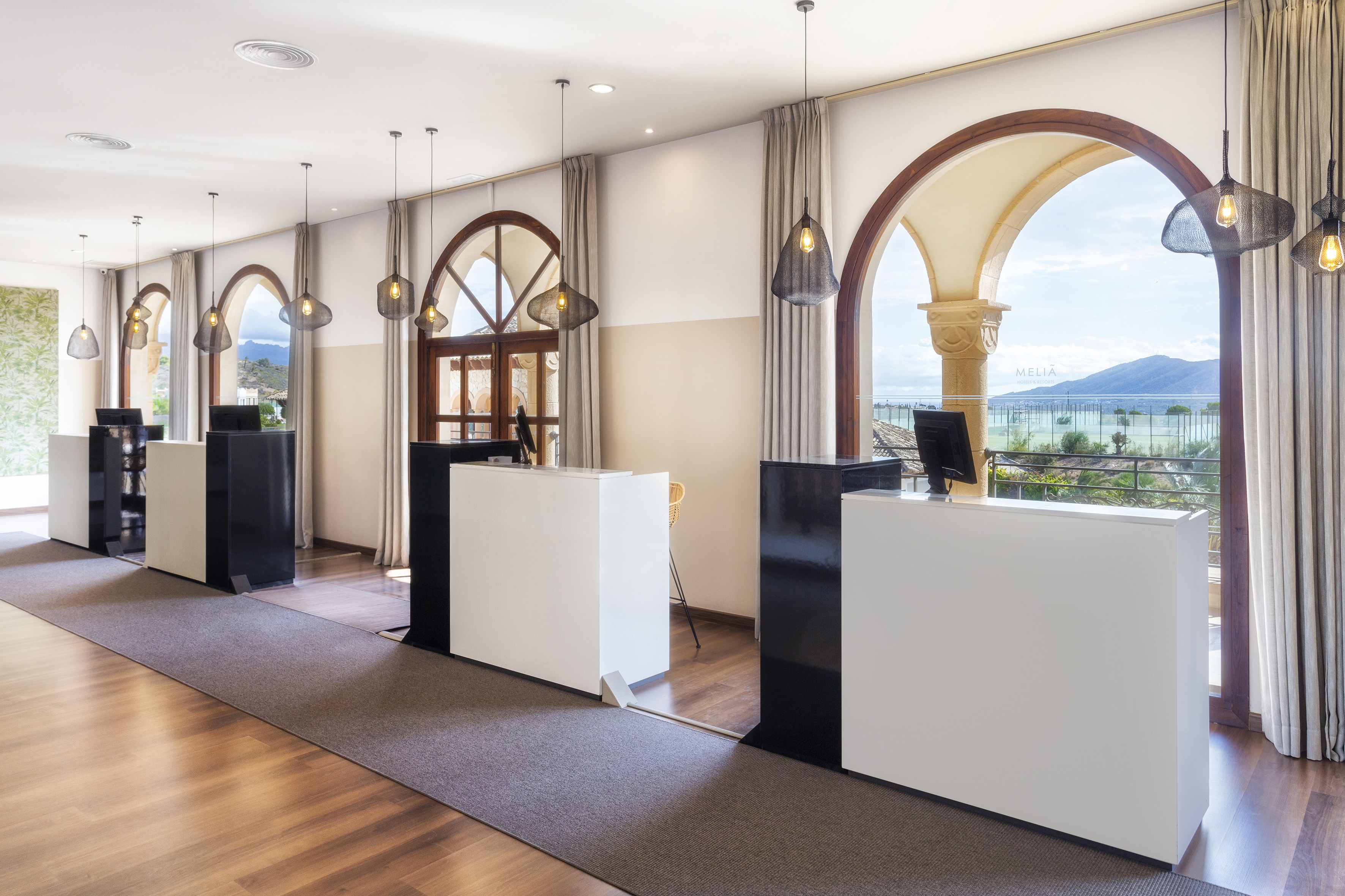 Meliá hotel reception with sleek white desks, arched windows, and mountain view.