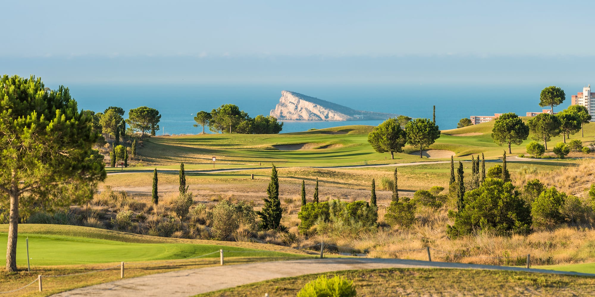 a golf course with trees and a body of water in the background