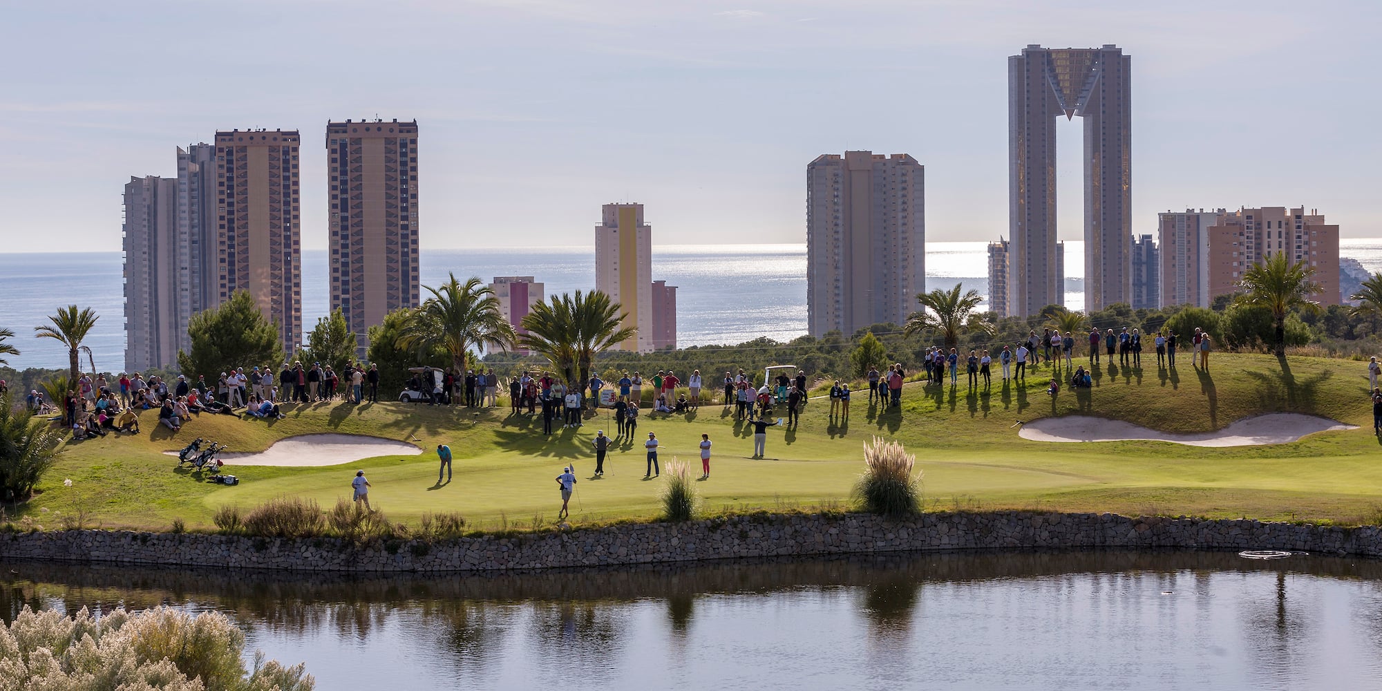 a group of people on a golf course by a body of water