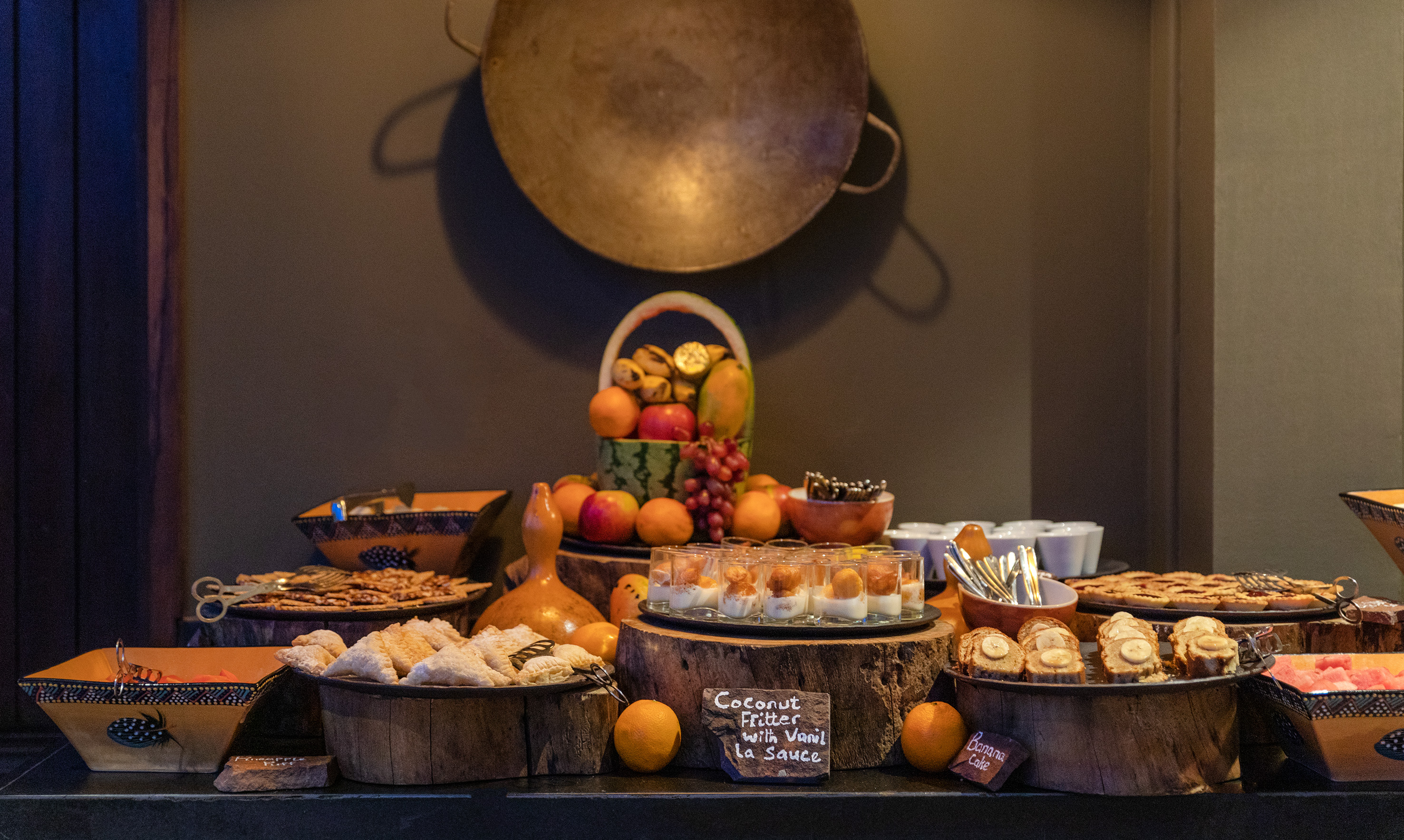 Tropical fruit and dessert buffet with coconut fritters and banana cake.