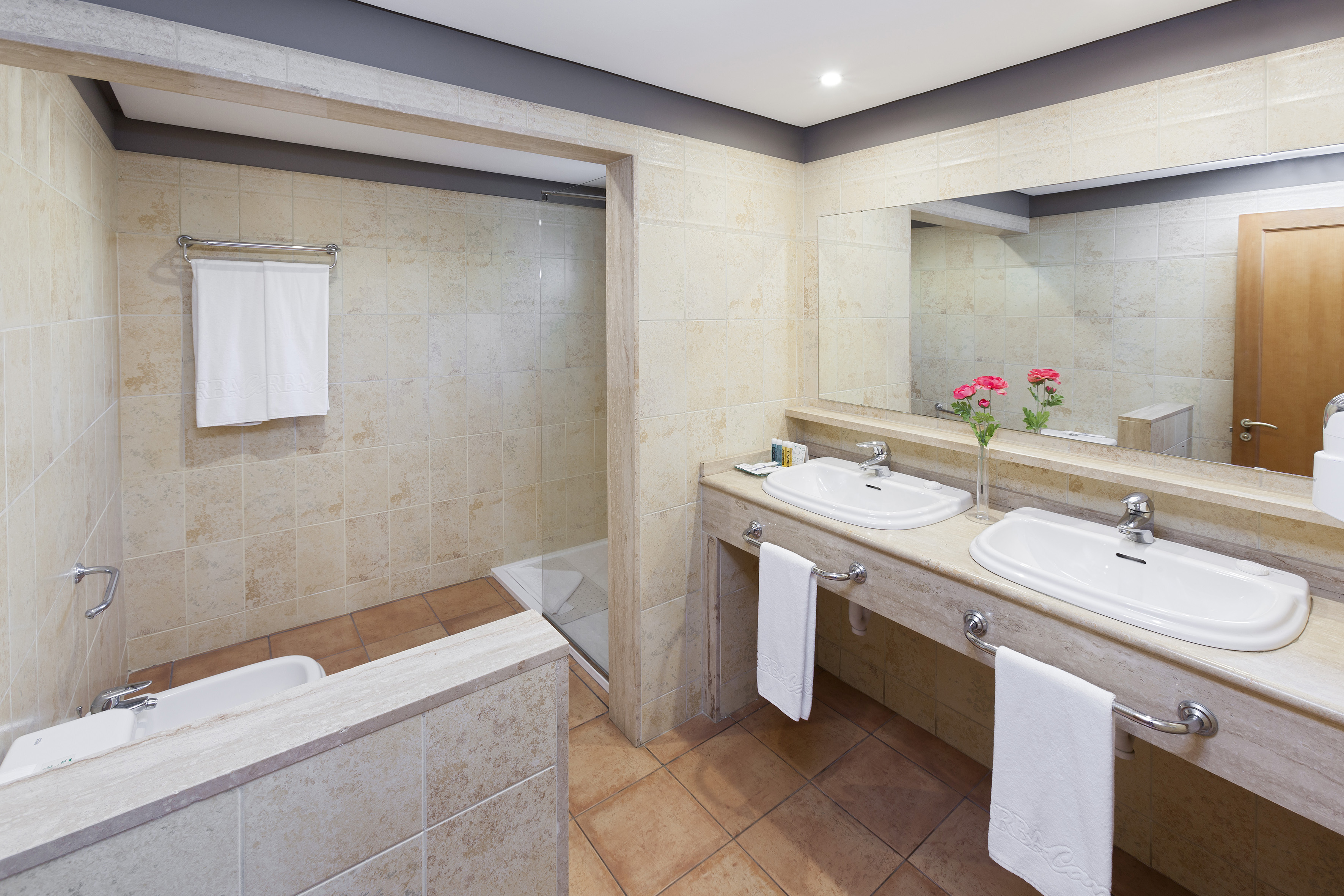 Tiled modern bathroom with double vanity, walk-in shower, and bidet.