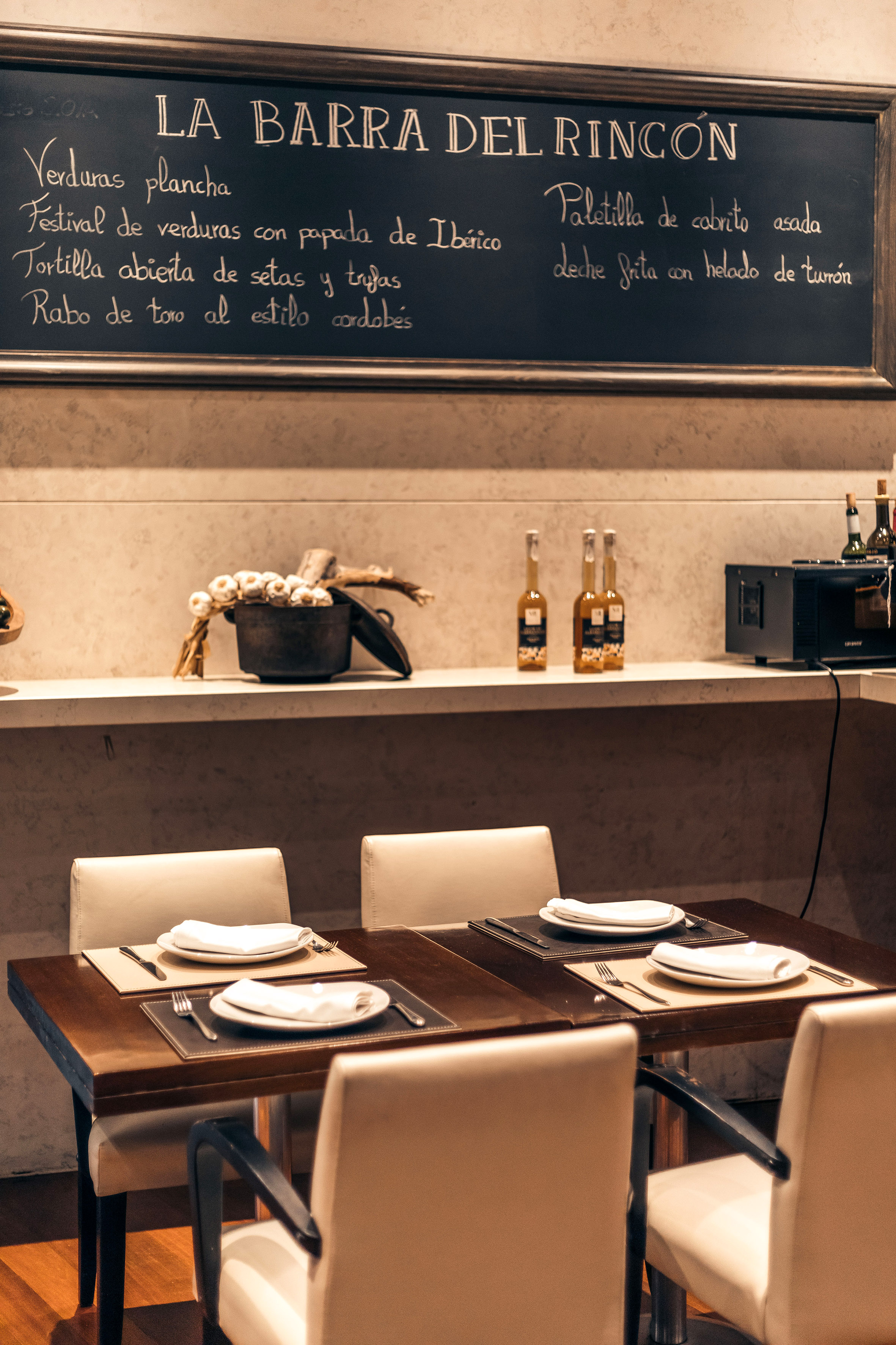 a table with white chairs and a blackboard on the wall