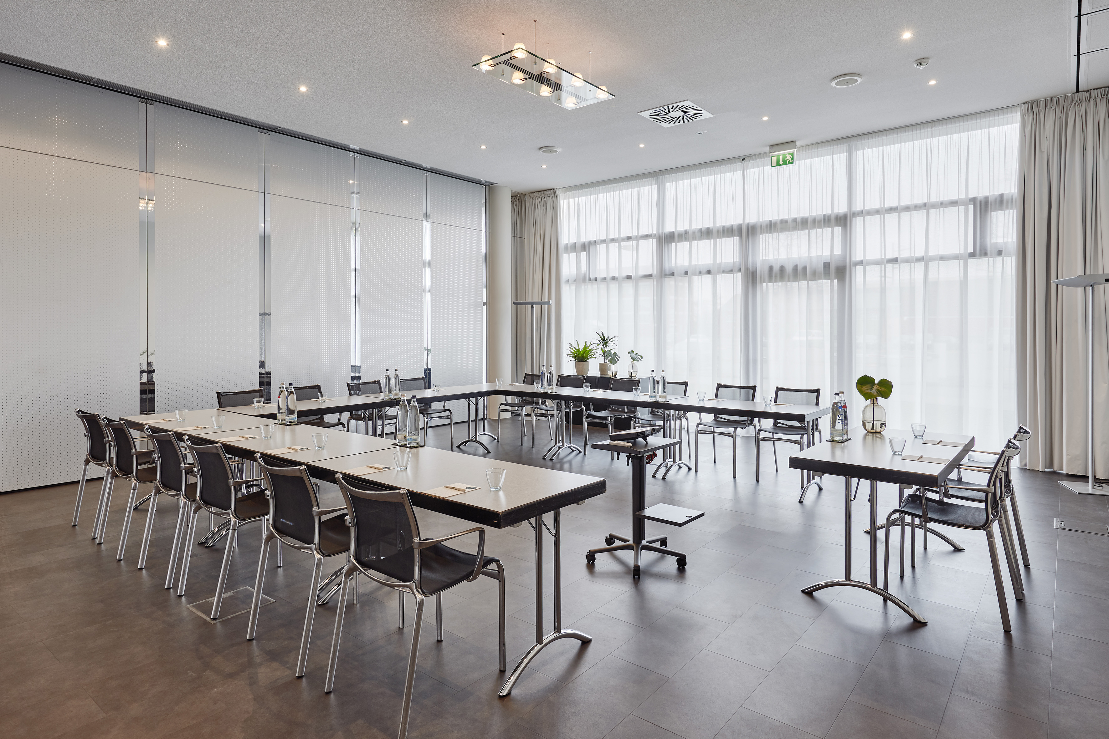 Professional U-shape conference room with tables, chairs, and frosted glass.