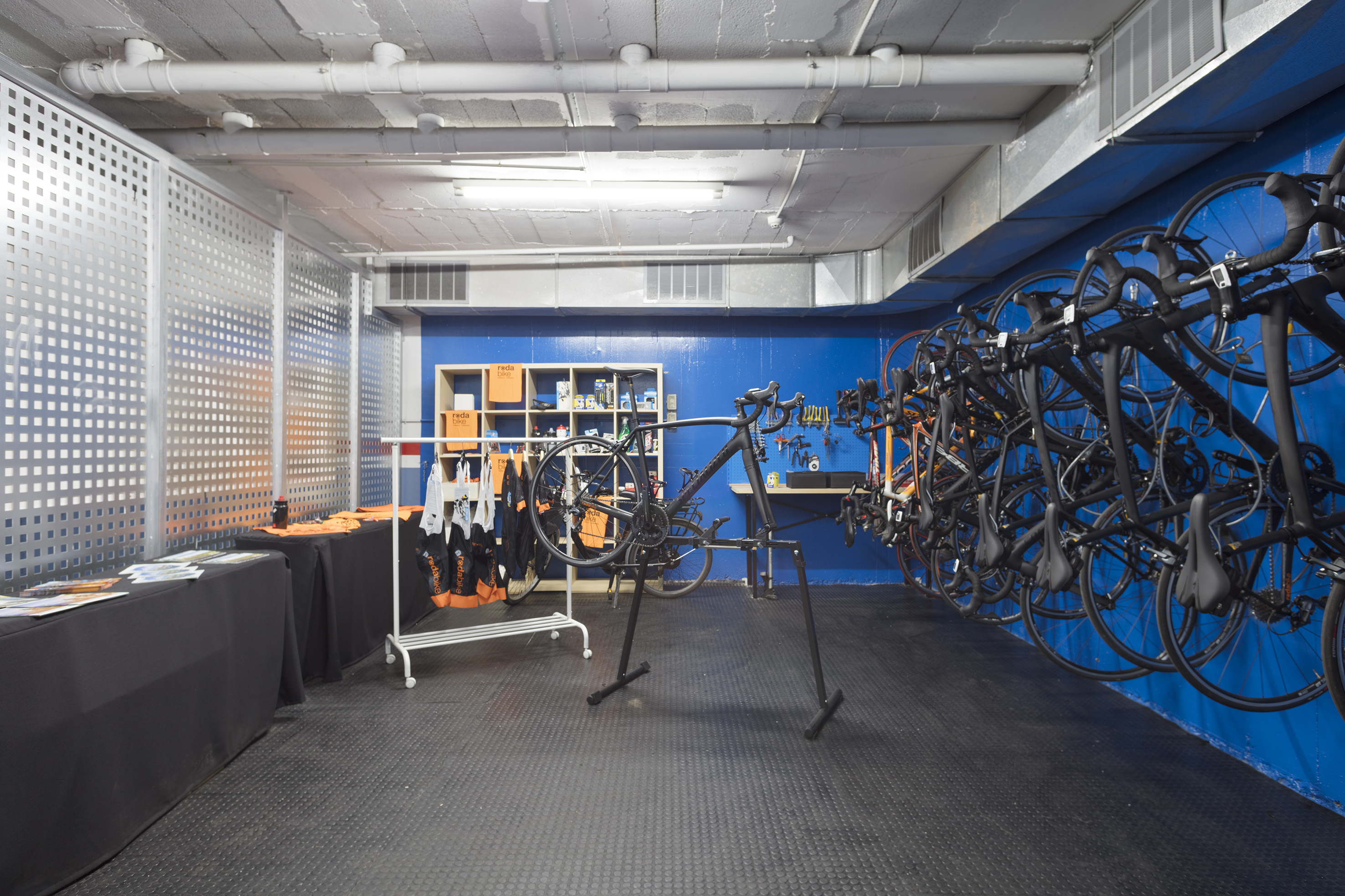 Bike workshop and storage with hanging bikes, repair stand, and retail gear.