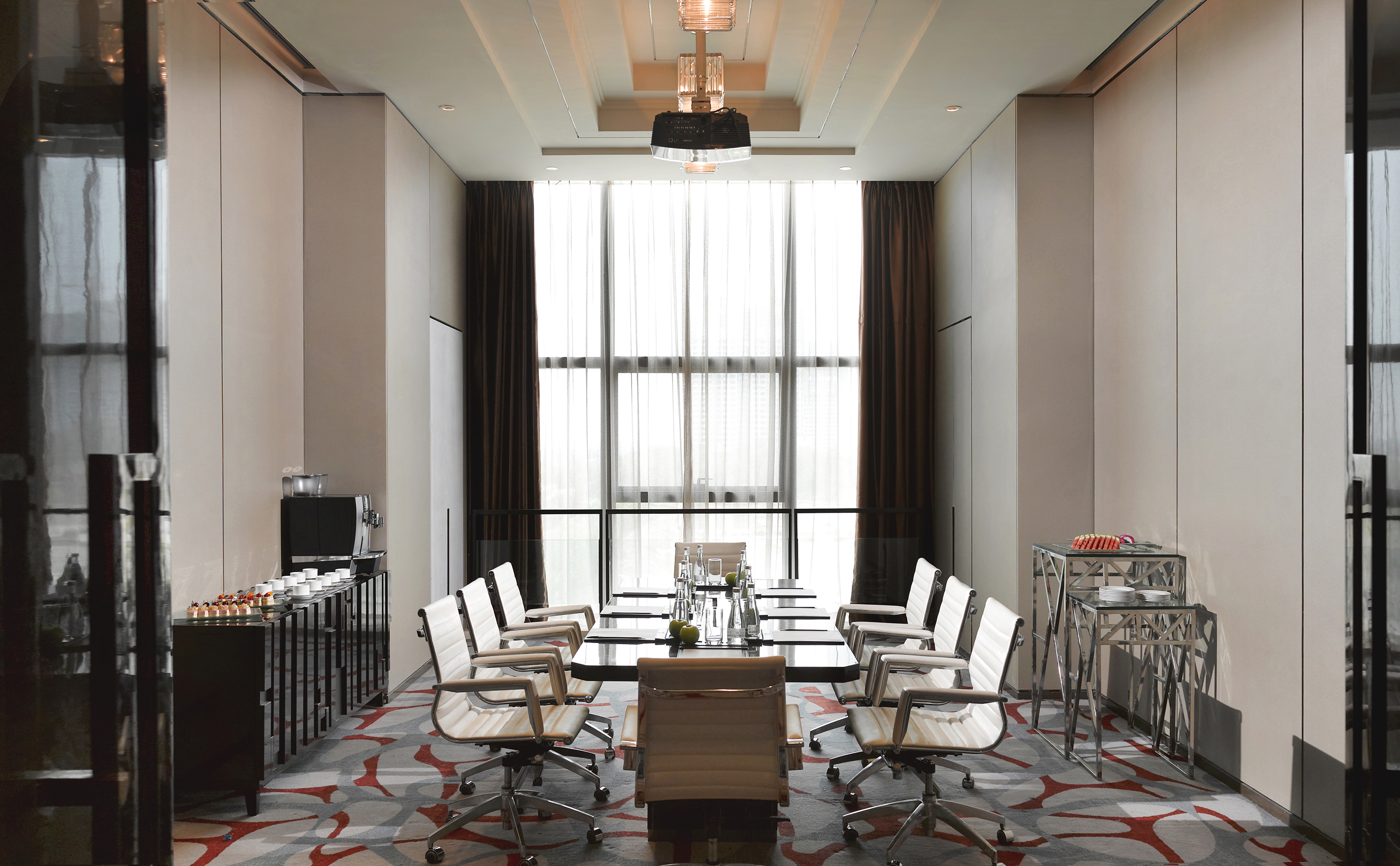 Modern meeting room with conference table, white chairs, and bright window.