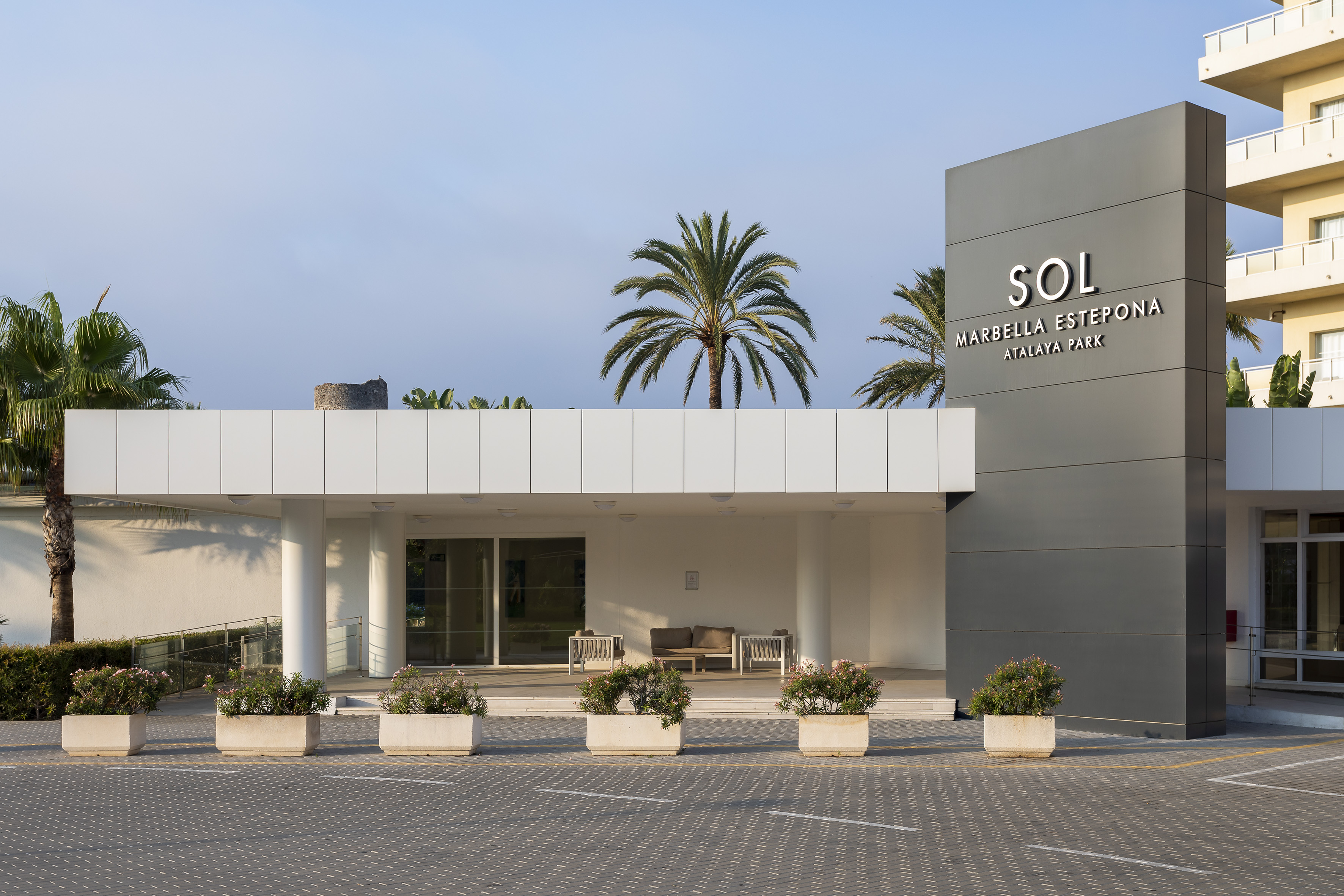 Sol Marbella Estepona Atalaya Park sign at modern hotel entrance with palm trees.