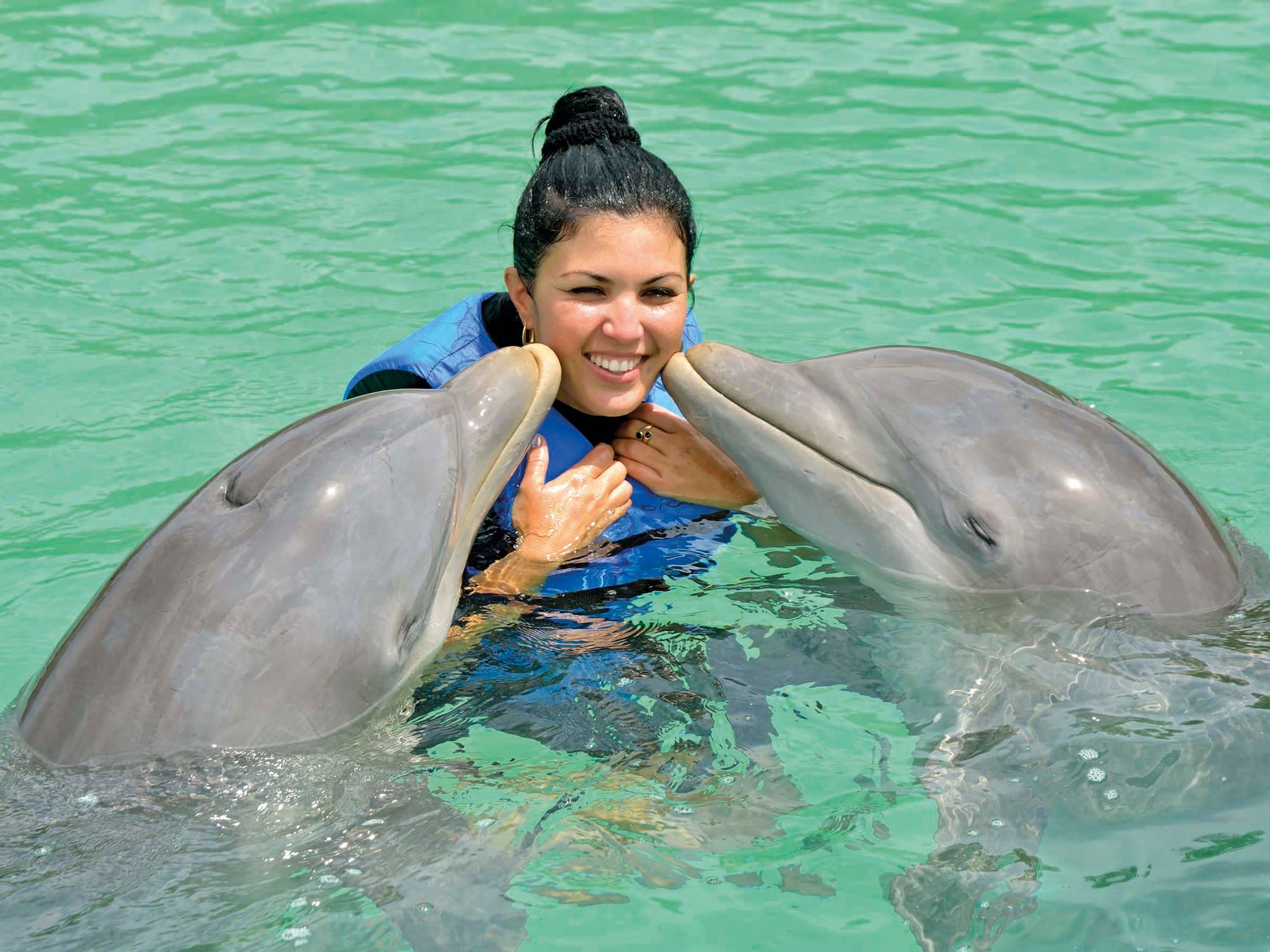 a woman with two dolphins in water