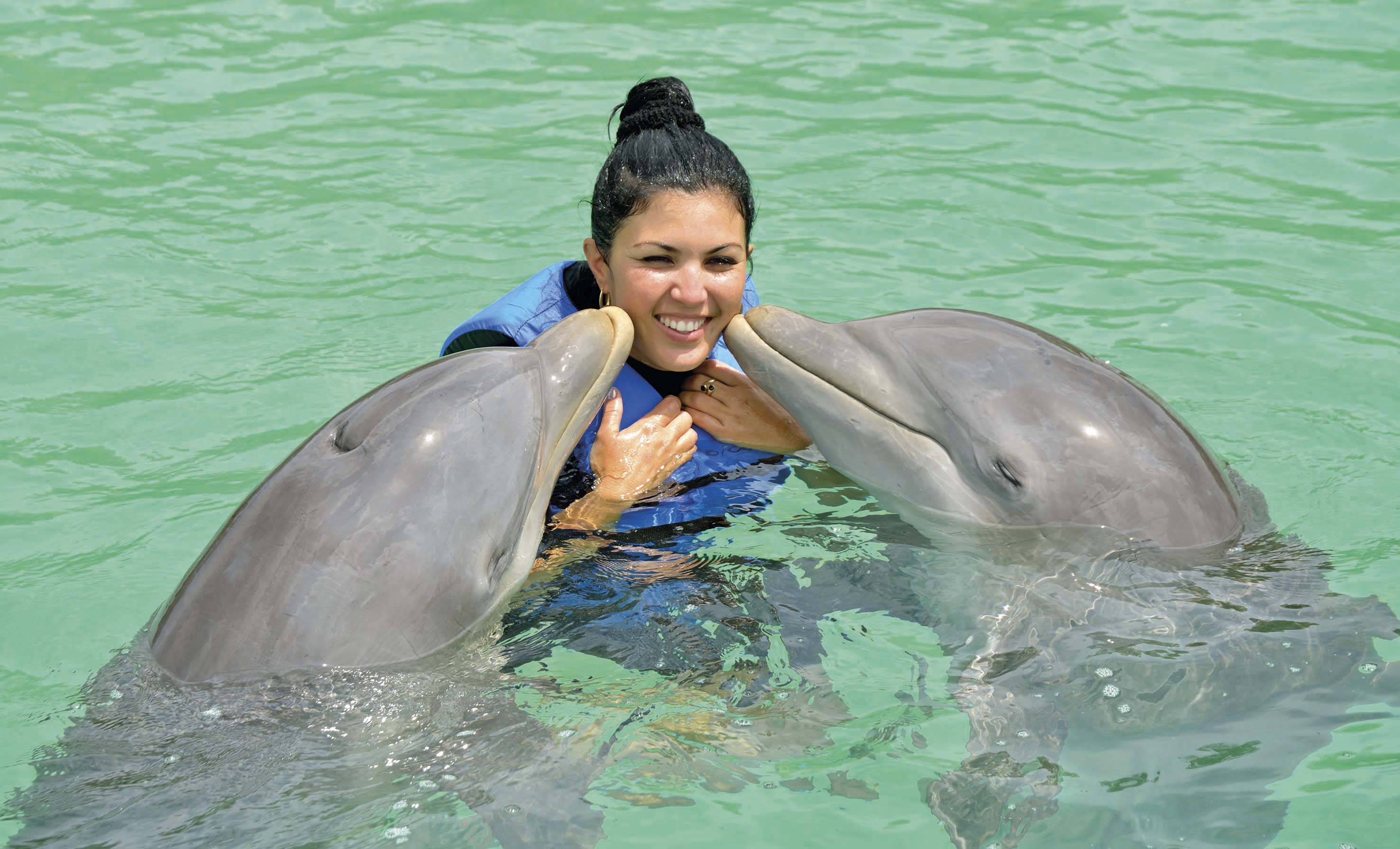 a woman with two dolphins in water