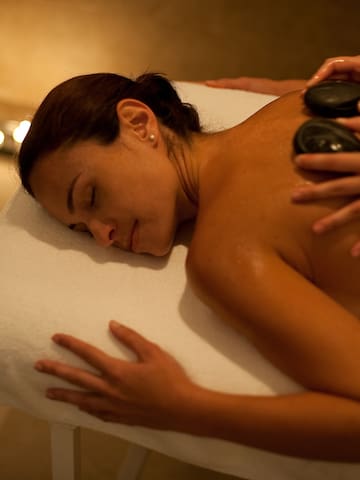 a woman lying on a massage table with a hot stone on her back
