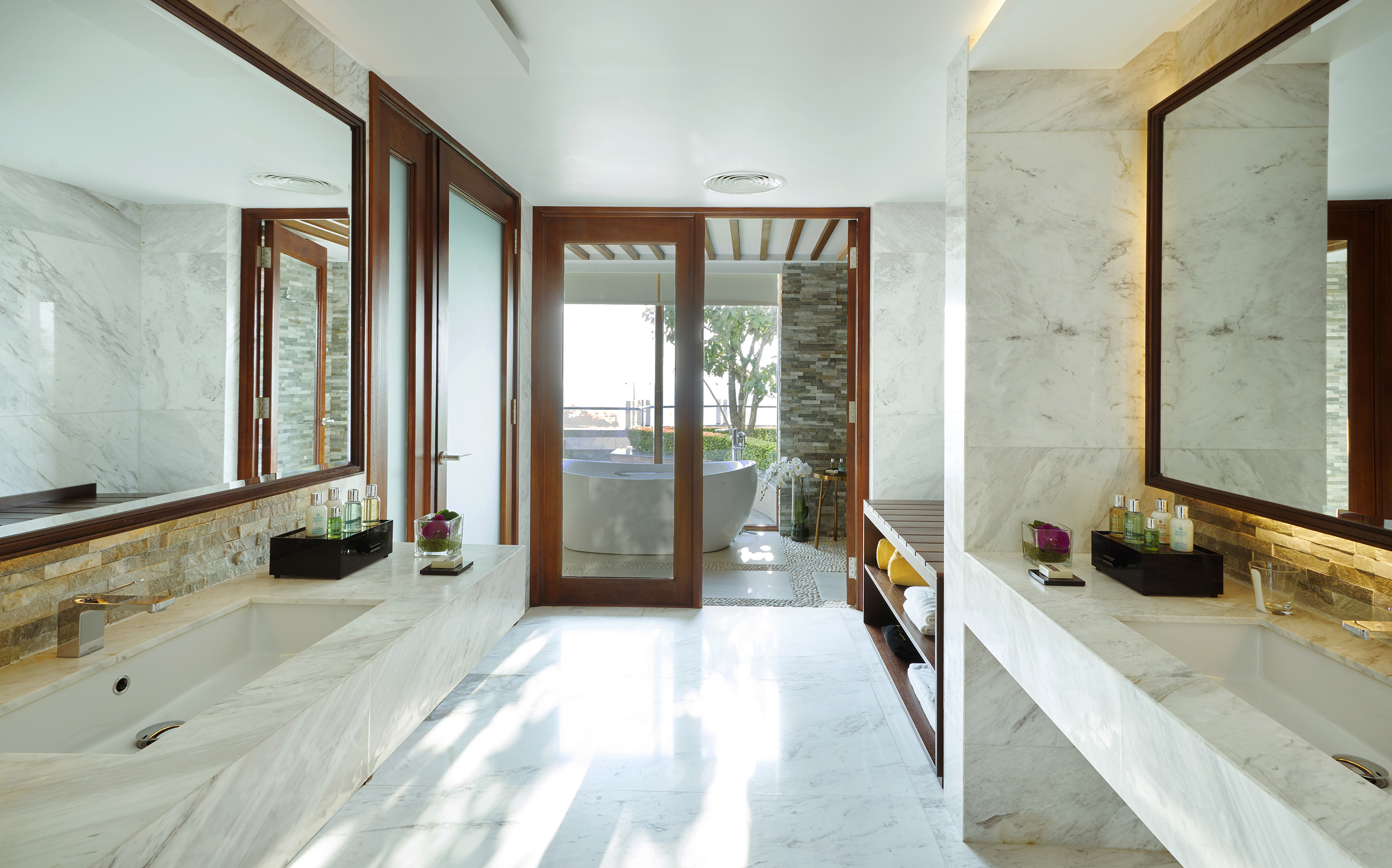 Luxurious marble bathroom with dual sinks and an outdoor freestanding tub.