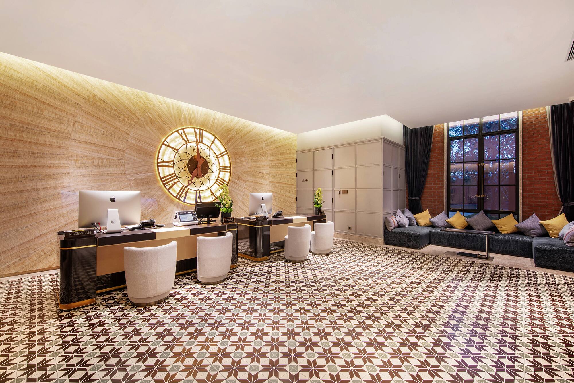 Modern hotel lobby with reception desk, large ornate clock, and patterned floor.