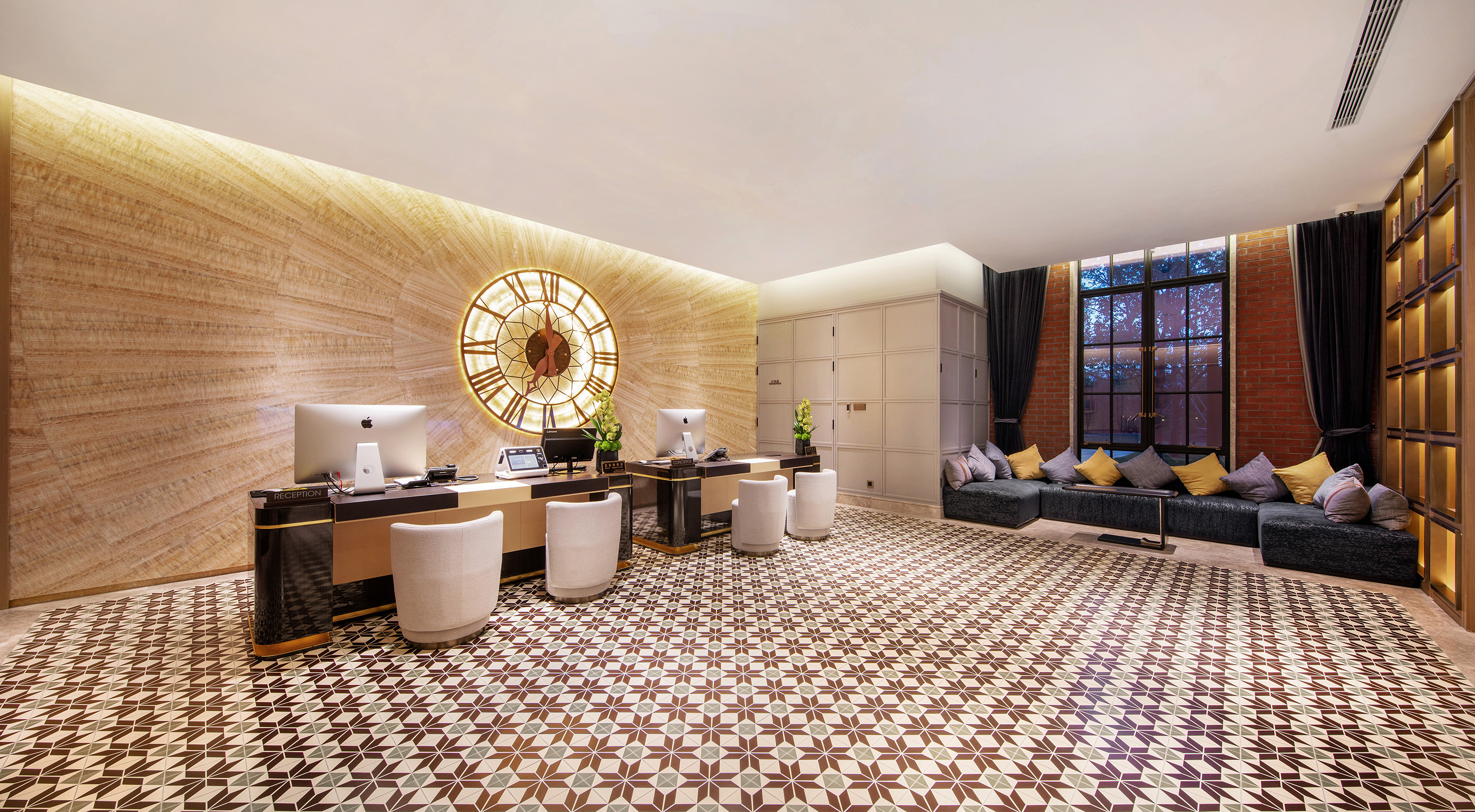 Modern hotel lobby with reception desk, large ornate clock, and patterned floor.