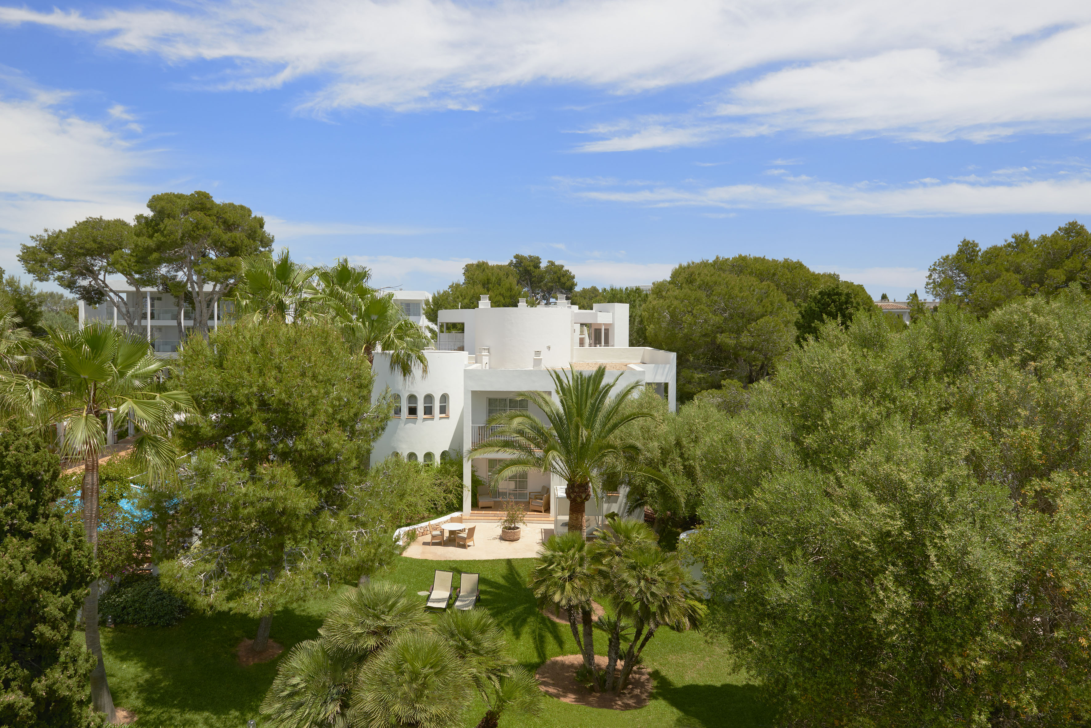 White Mediterranean villa nestled in lush palm gardens with outdoor patio.