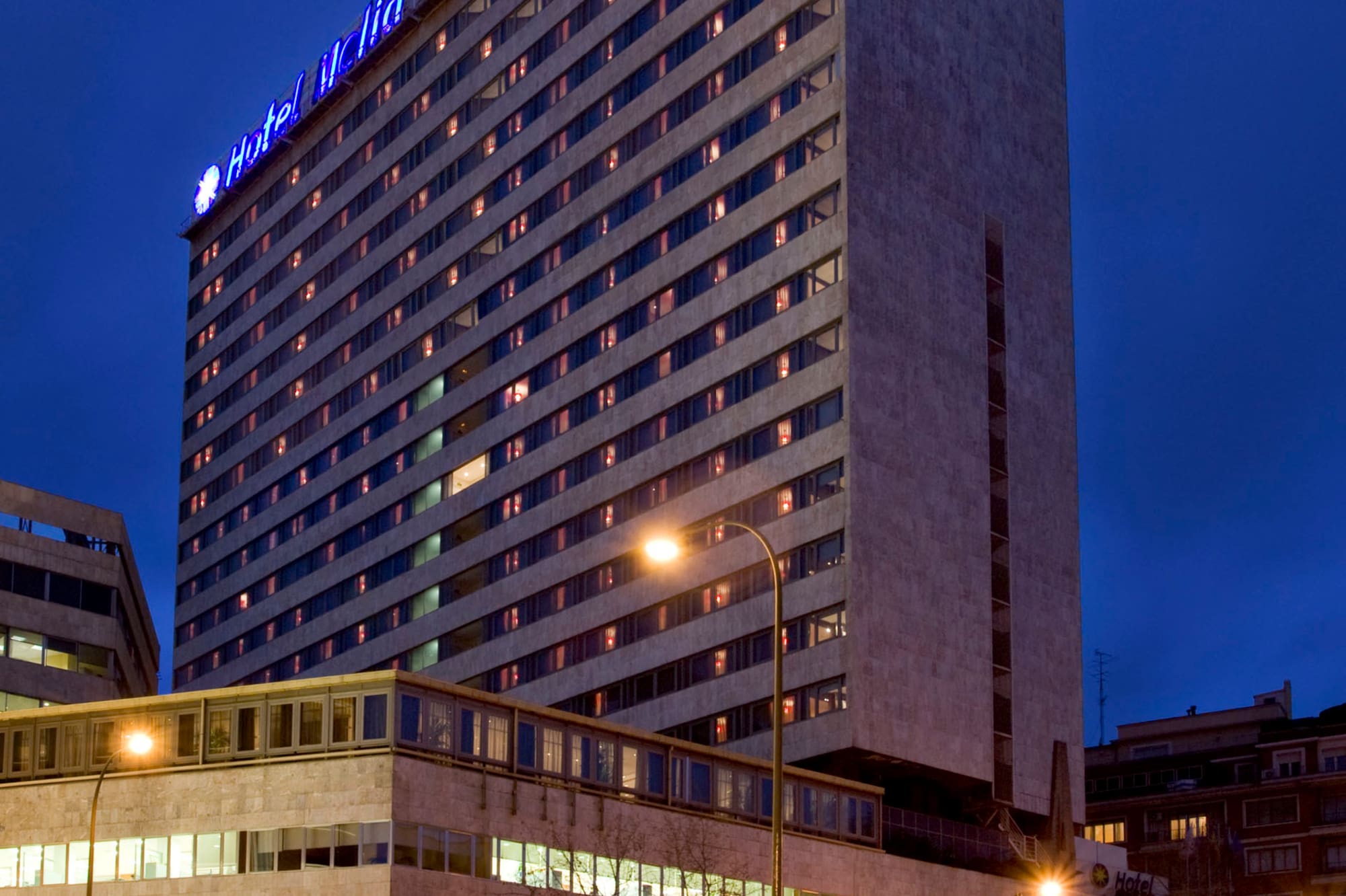 Hotel Meliá Madrid Princesa tower with glowing blue sign, night city.