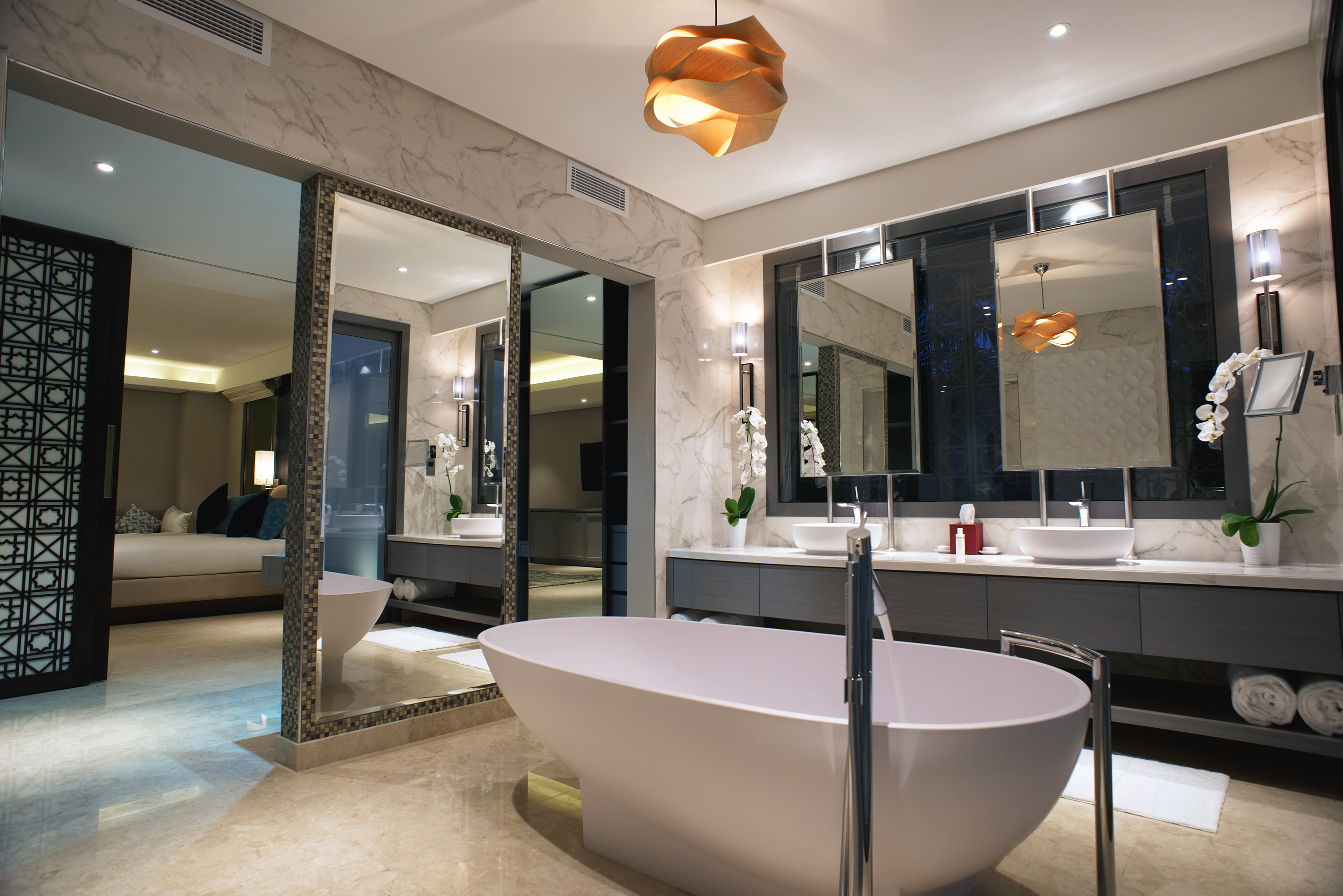 Luxury bathroom with freestanding tub, double vanity, and marble walls.
