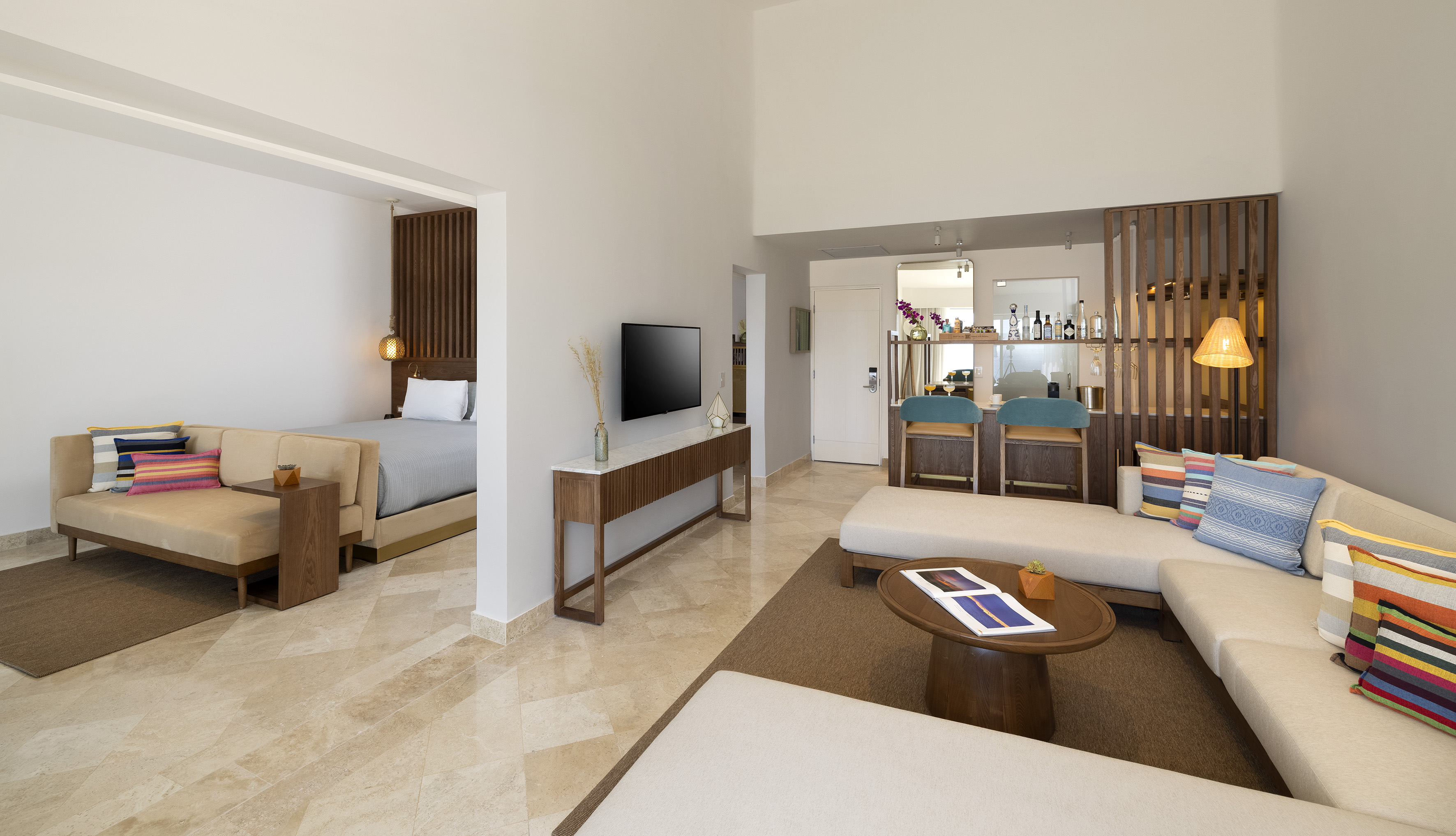 Modern hotel suite with open living area, bedroom, and sleek bar.