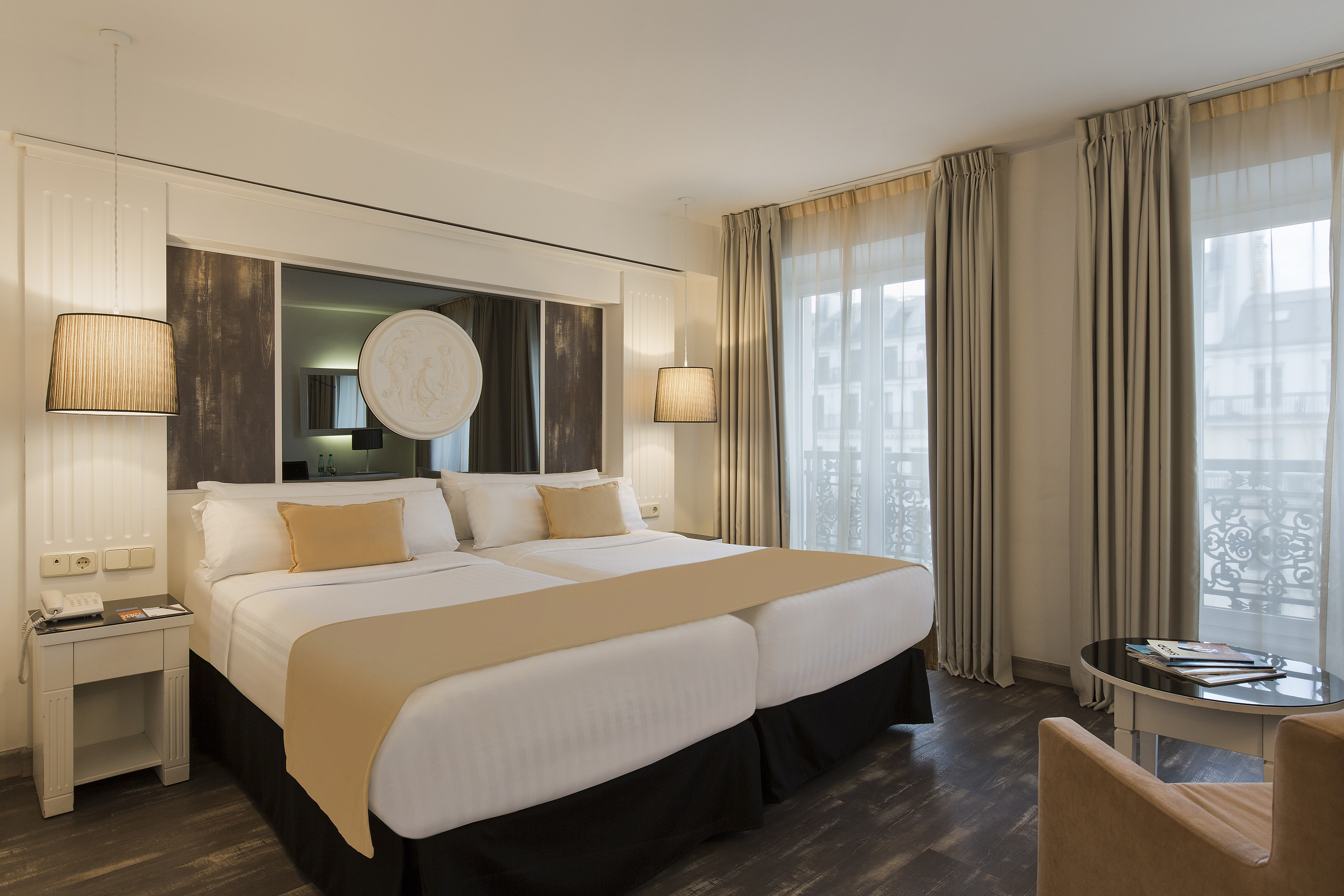 Hotel room with two twin beds, elegant decor, and large window.