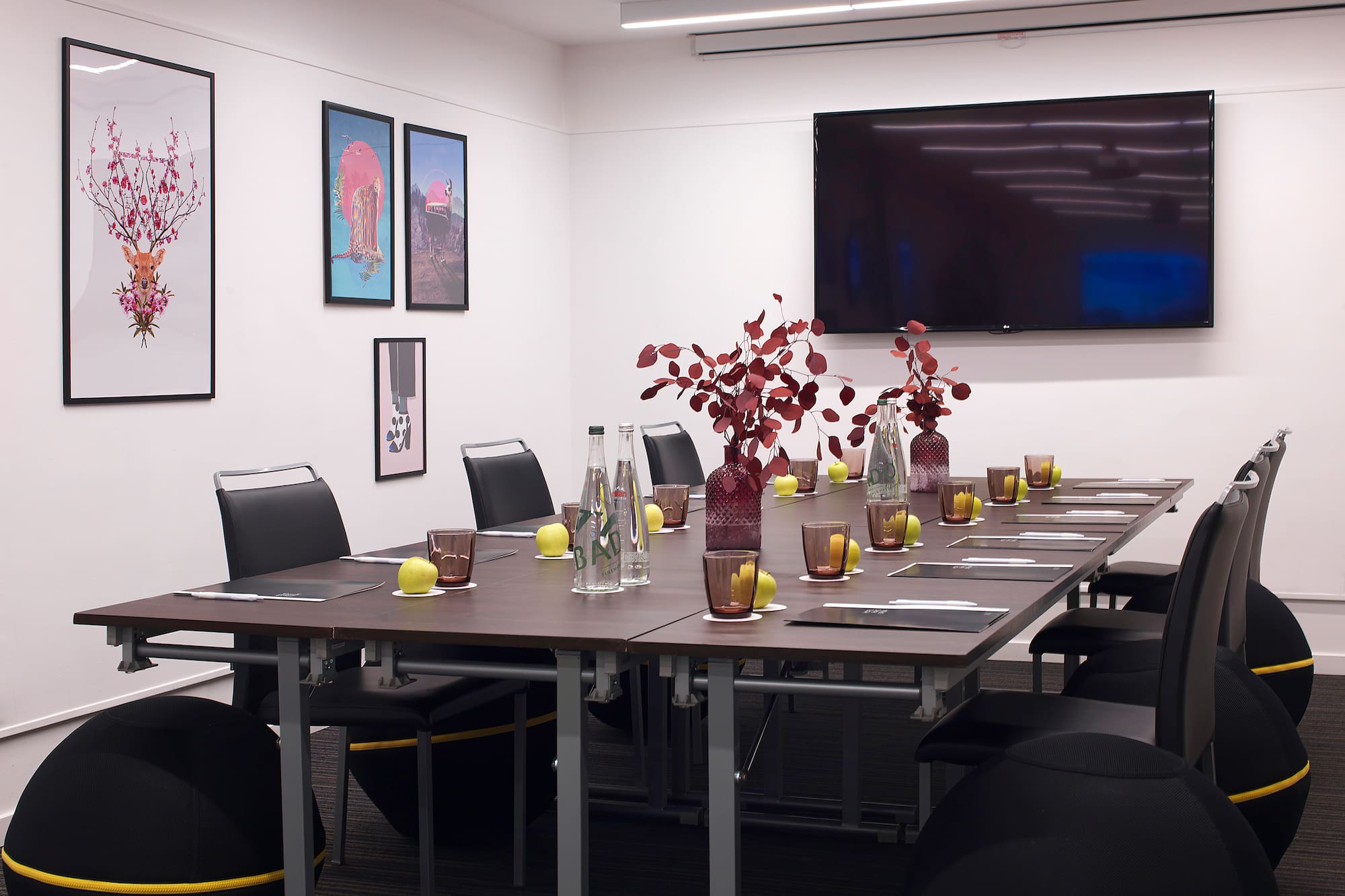 a table with vases of flowers and chairs in a room with a television