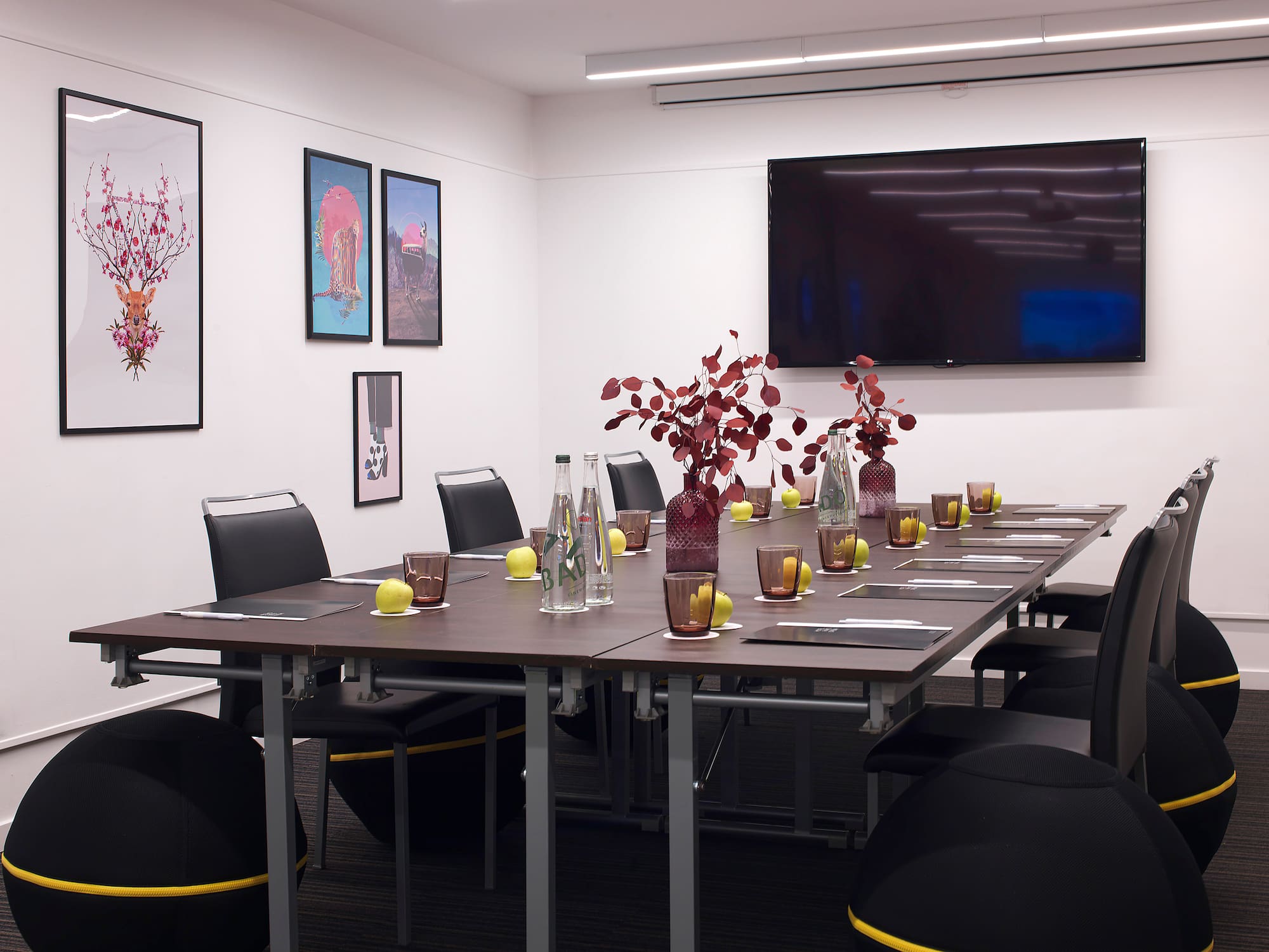 a table with vases of flowers and chairs in a room with a television