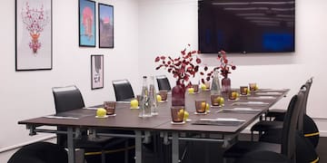 a table with vases of flowers and chairs in a room with a television
