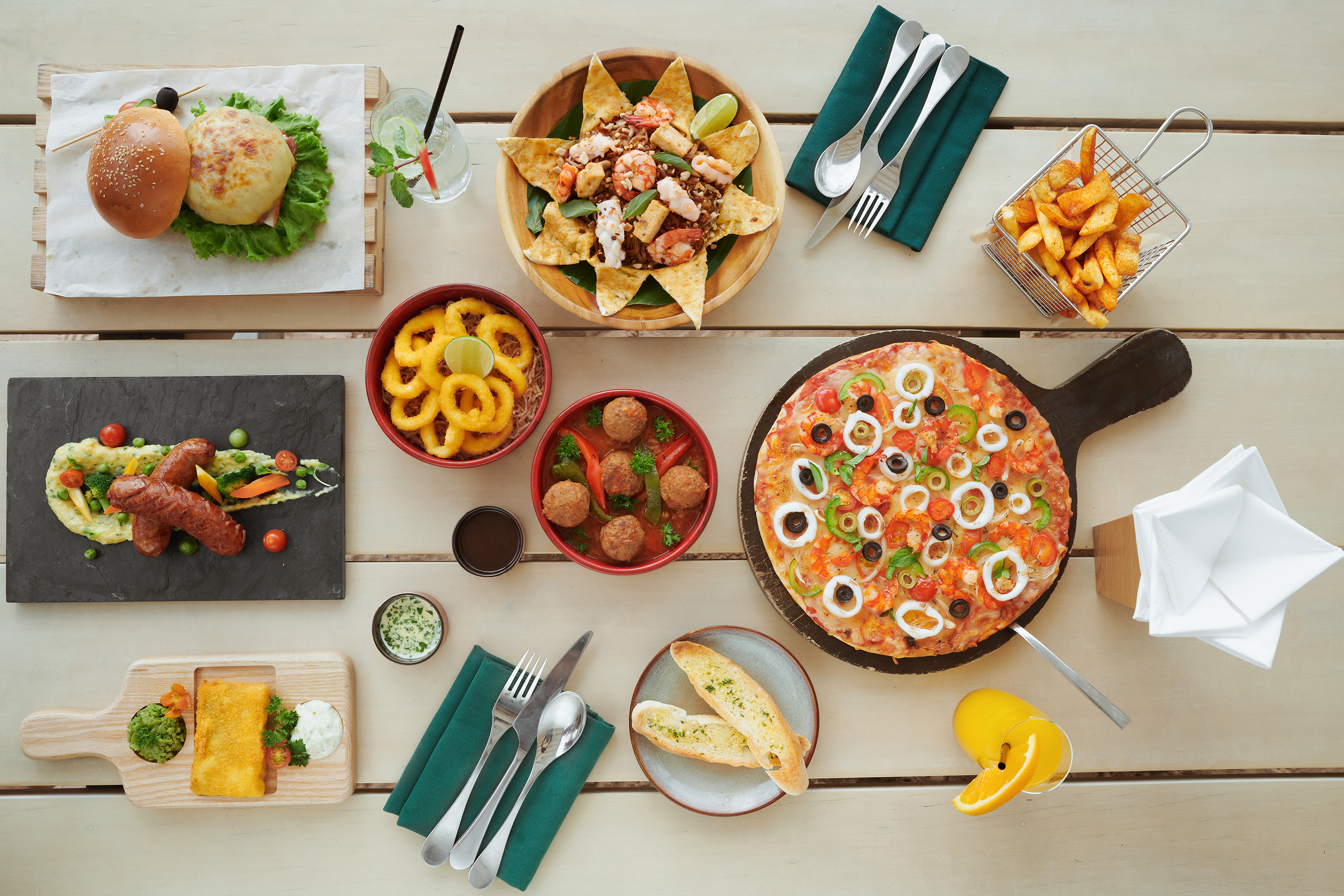 Diverse restaurant meal spread: pizza, burgers, seafood, fries, calamari.