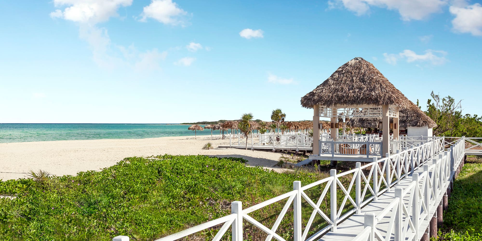 a white walkway leading to a beach