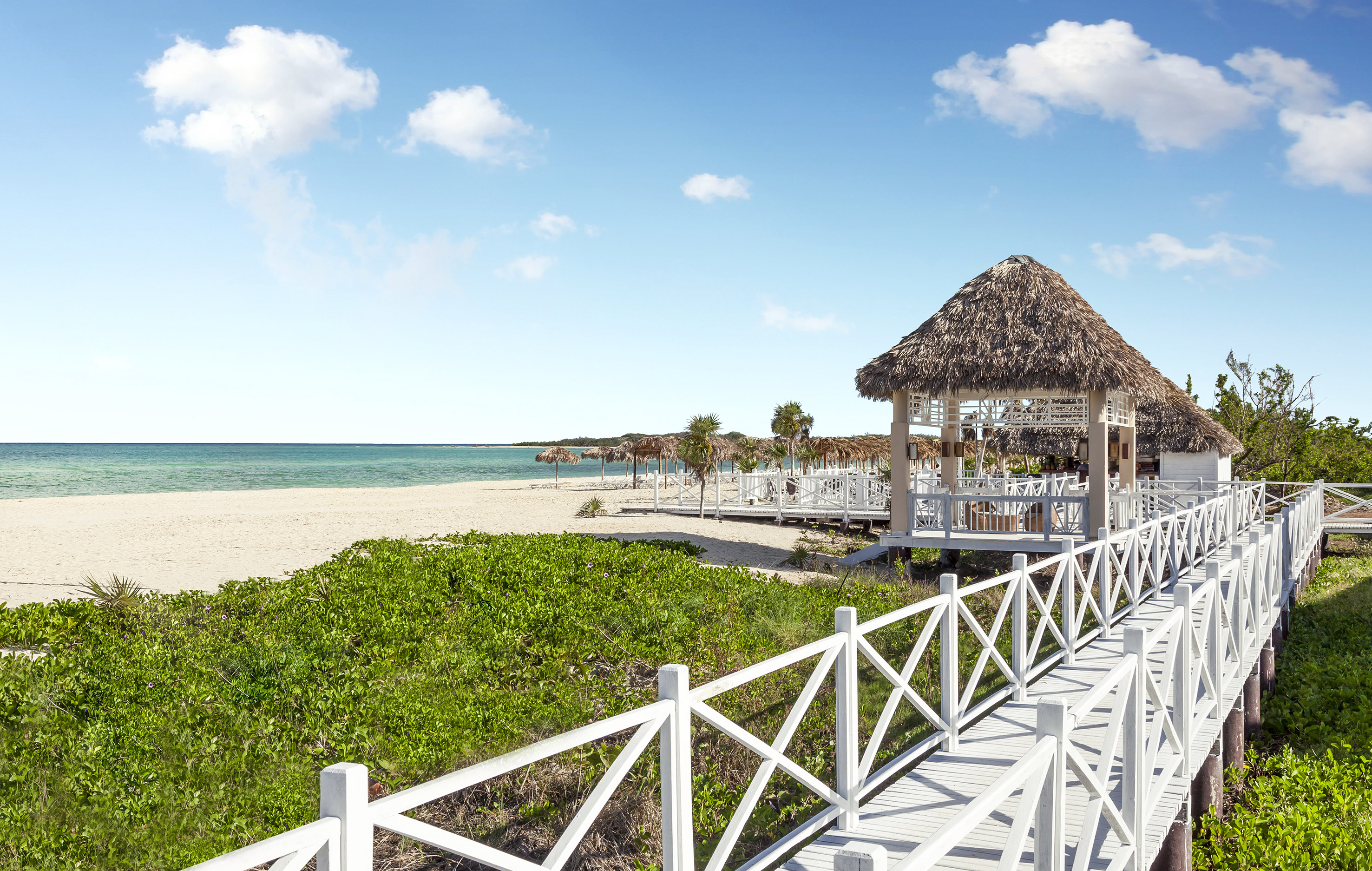 a white walkway leading to a beach