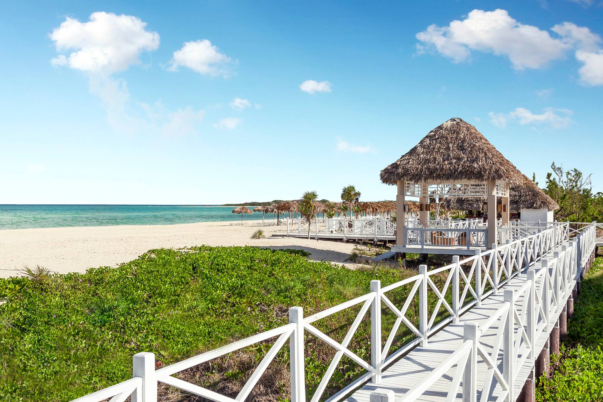 a white walkway leading to a beach