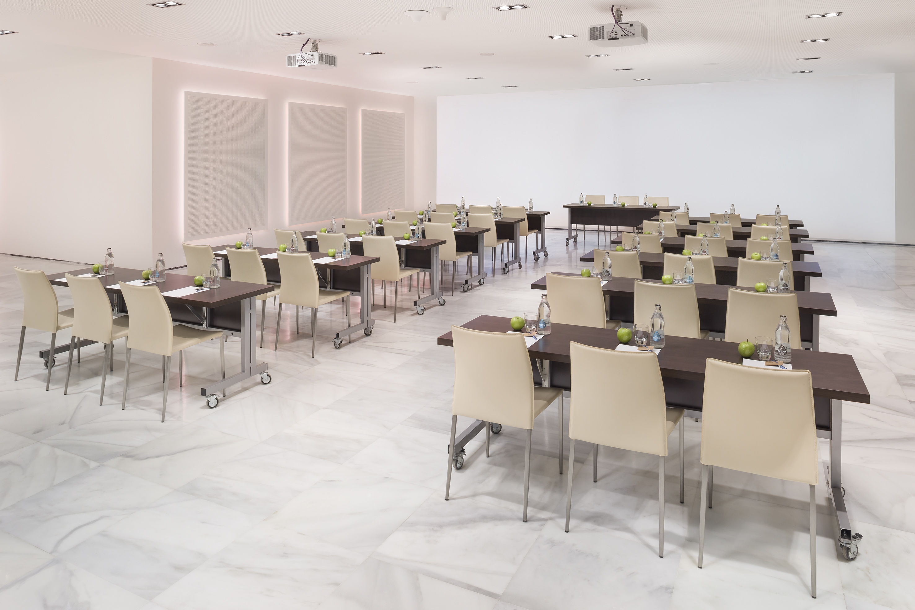 Modern conference room with tables, beige chairs, and presentation equipment.