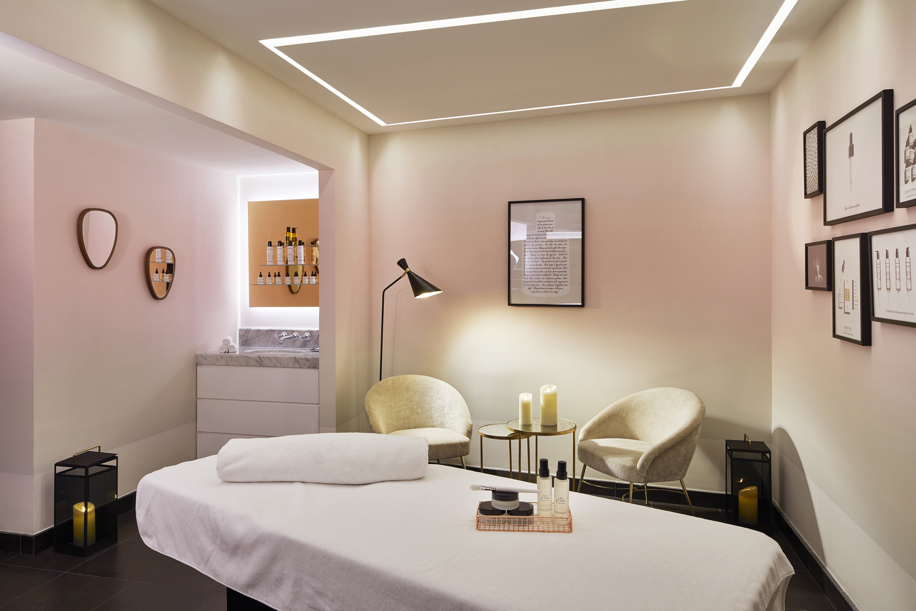 Modern spa treatment room with massage table, skincare products, and seating.
