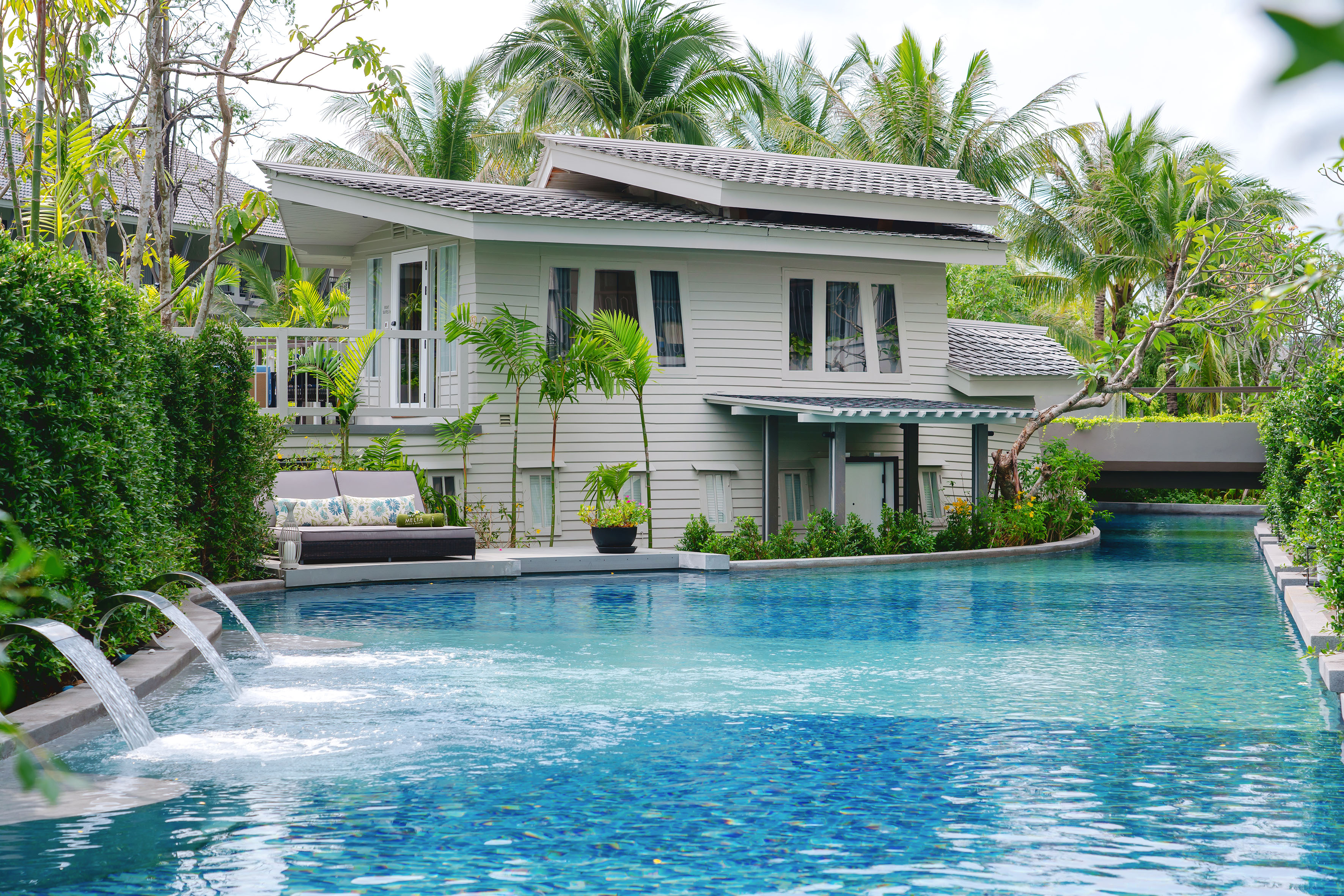 Luxury tropical resort villa with swimming pool and palm trees.