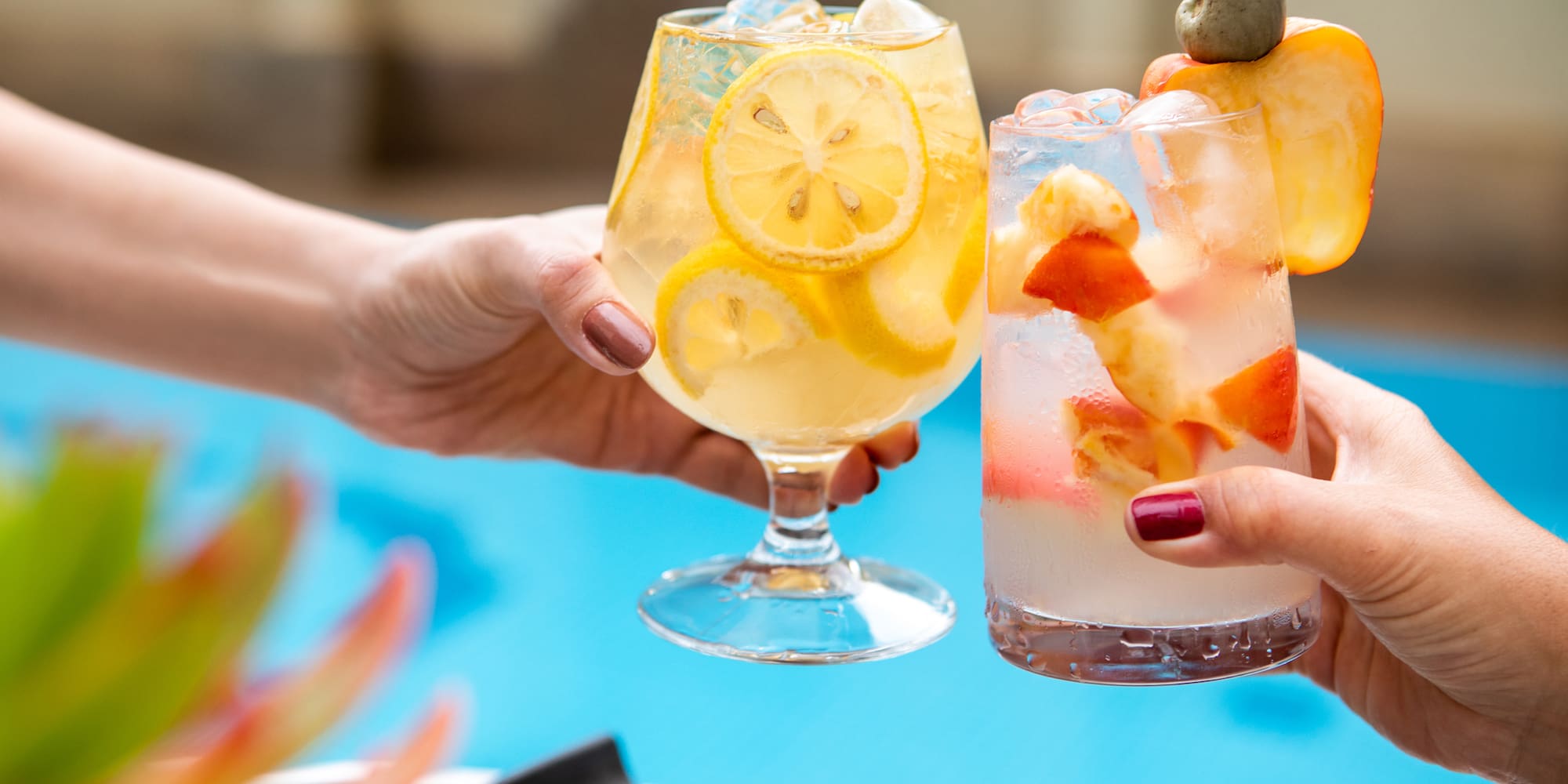 a pair of hands holding glasses with fruit