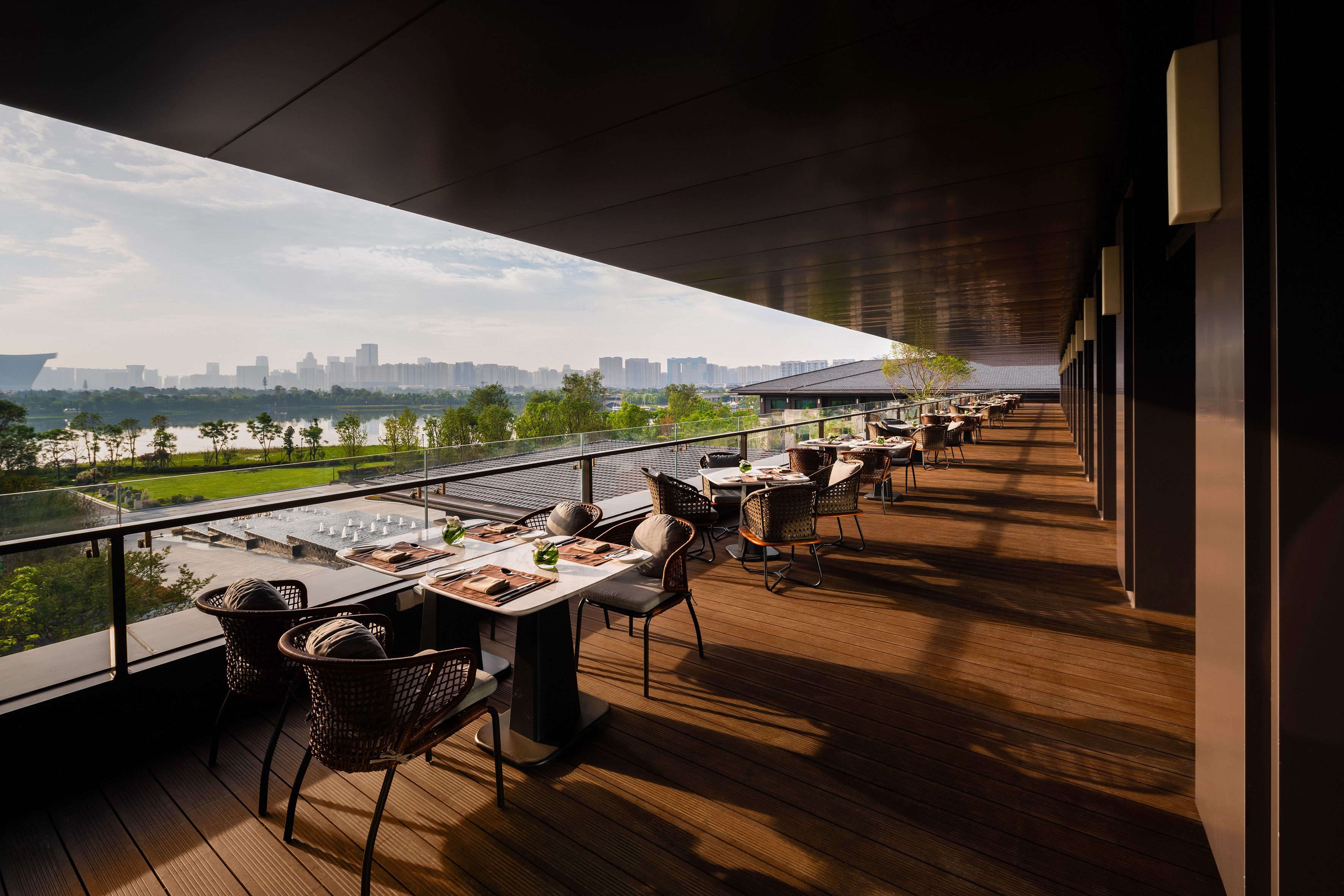 Lakeside restaurant terrace, outdoor dining with city skyline view.