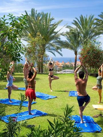 a group of people doing yoga on mats in a grassy area