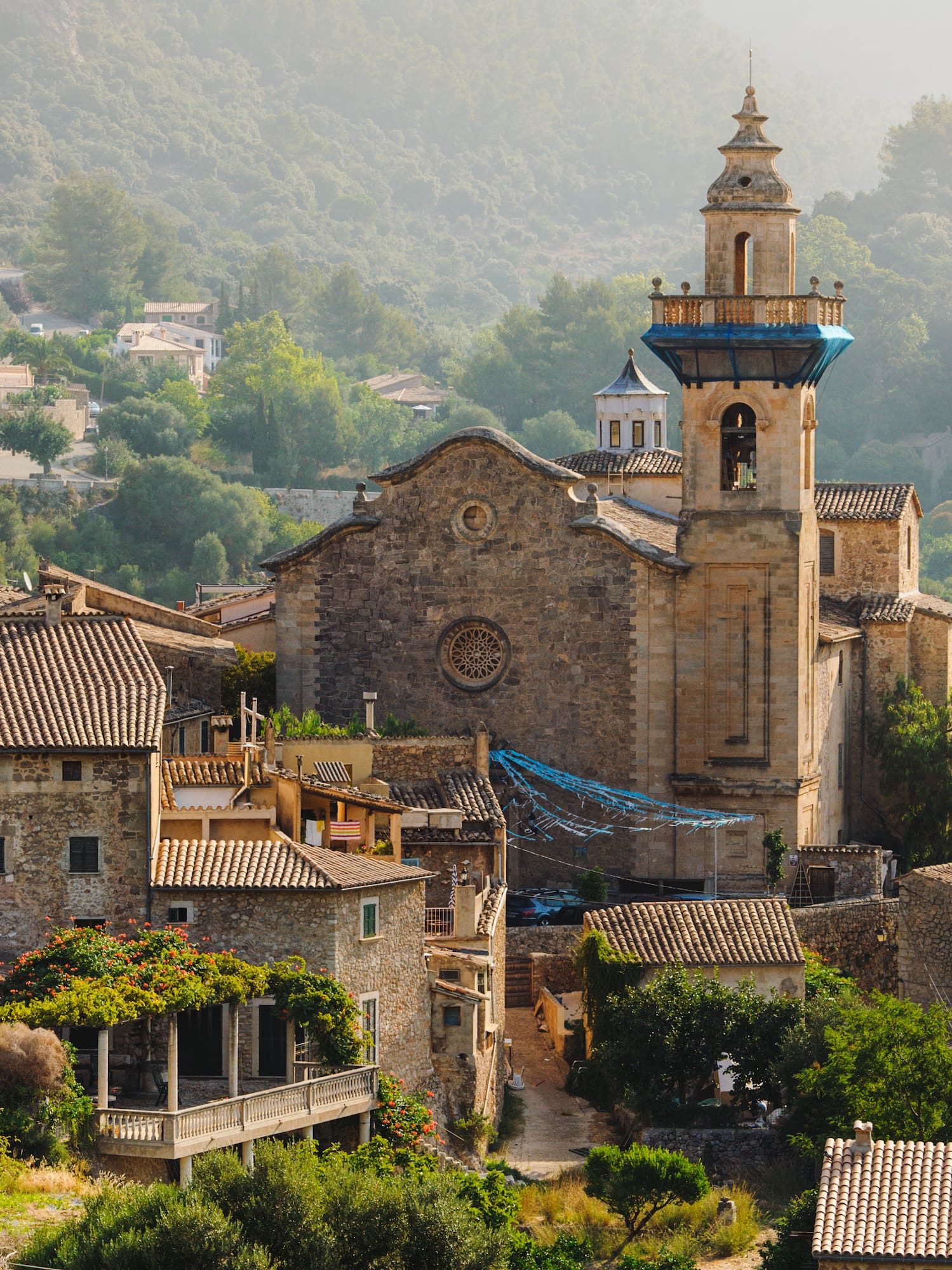 a stone building with a tower and a steeple in a village
