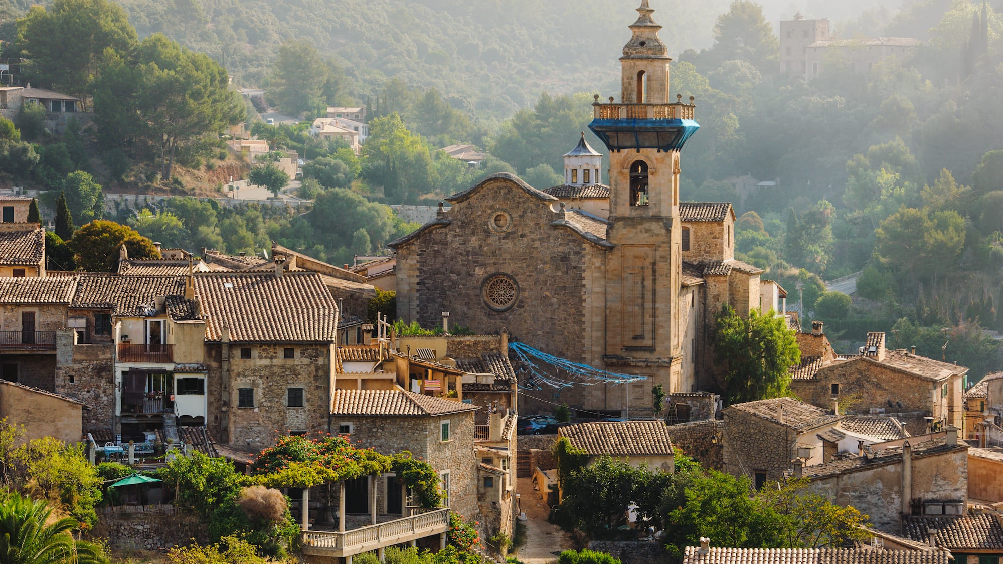 a stone building with a tower and a steeple in a village