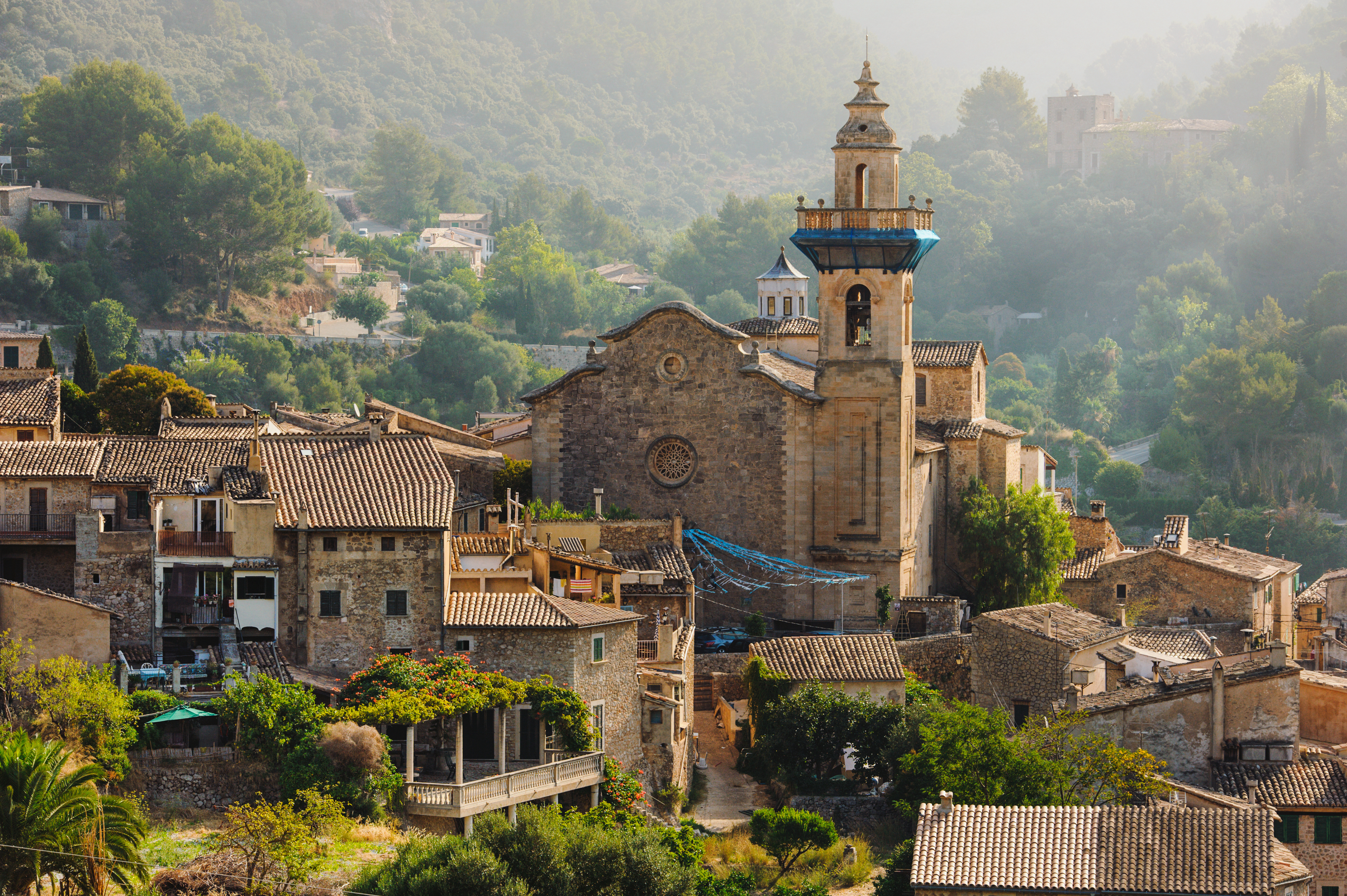 Historic mountain village, stone church with bell tower, and tiled roofs.
