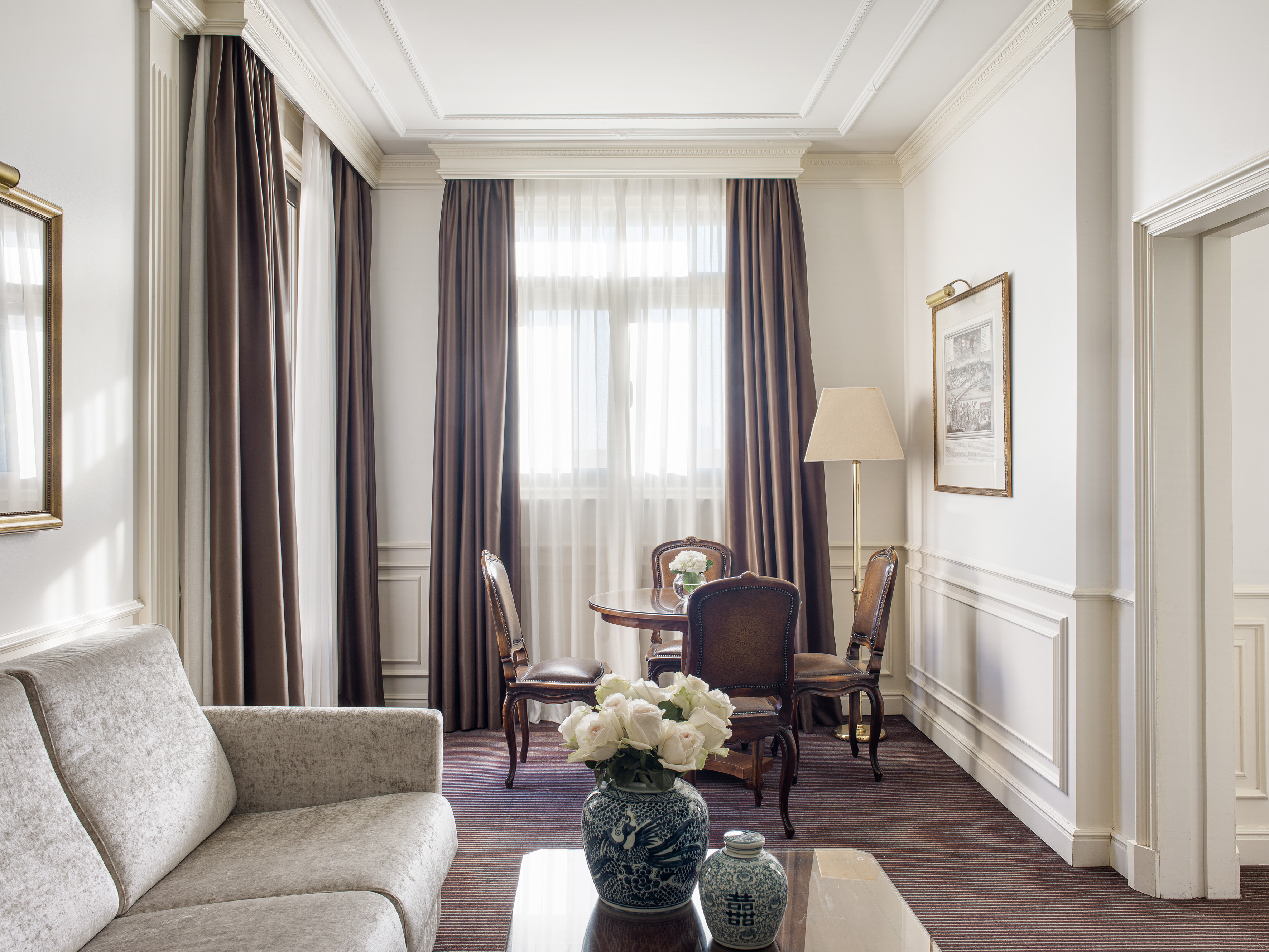 Elegant hotel suite with classic decor, sofa, and a dining table.
