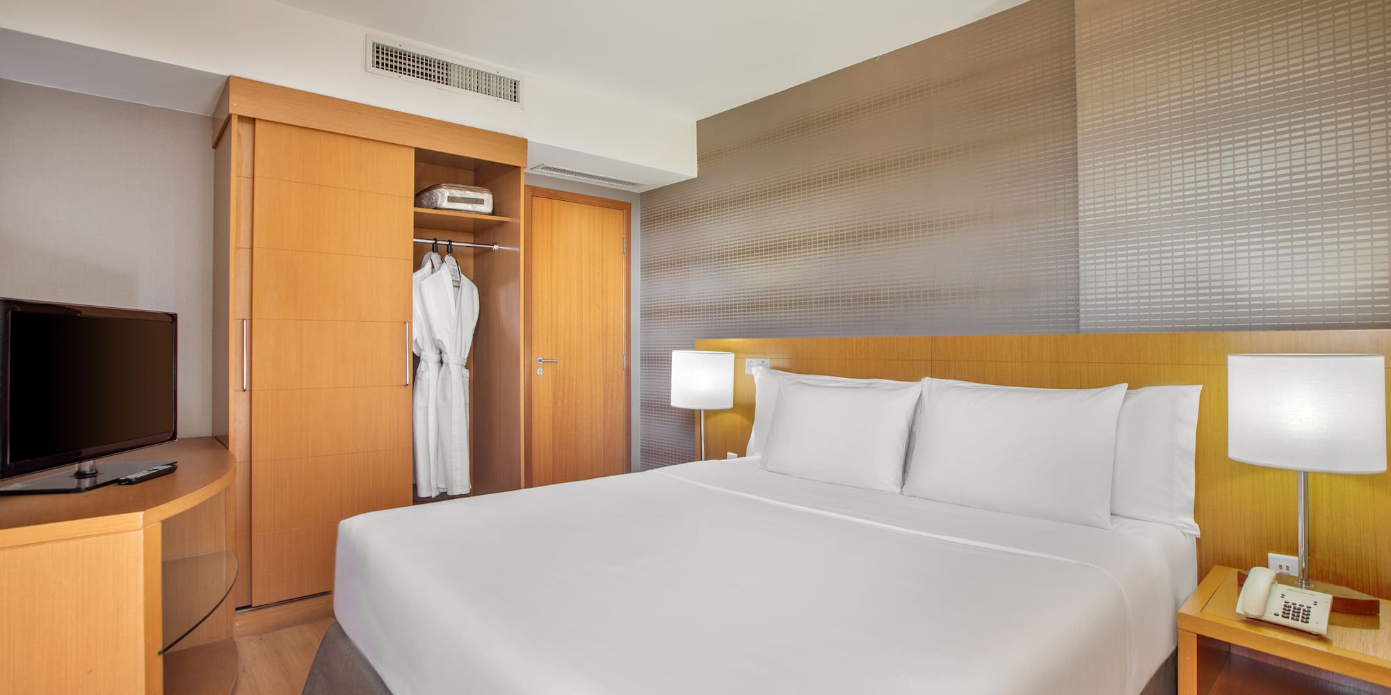 a bed with white sheets and a white robe in a room