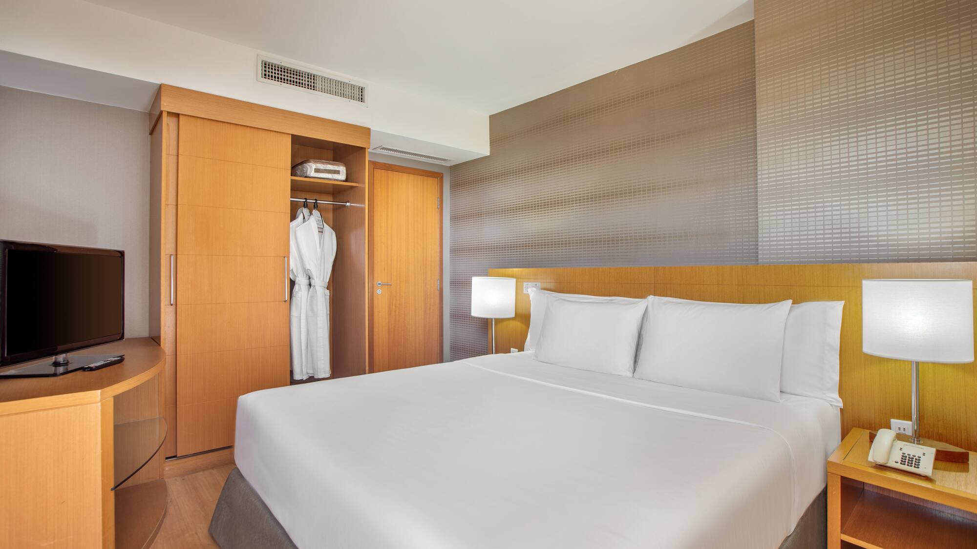 a bed with white sheets and a white robe in a room