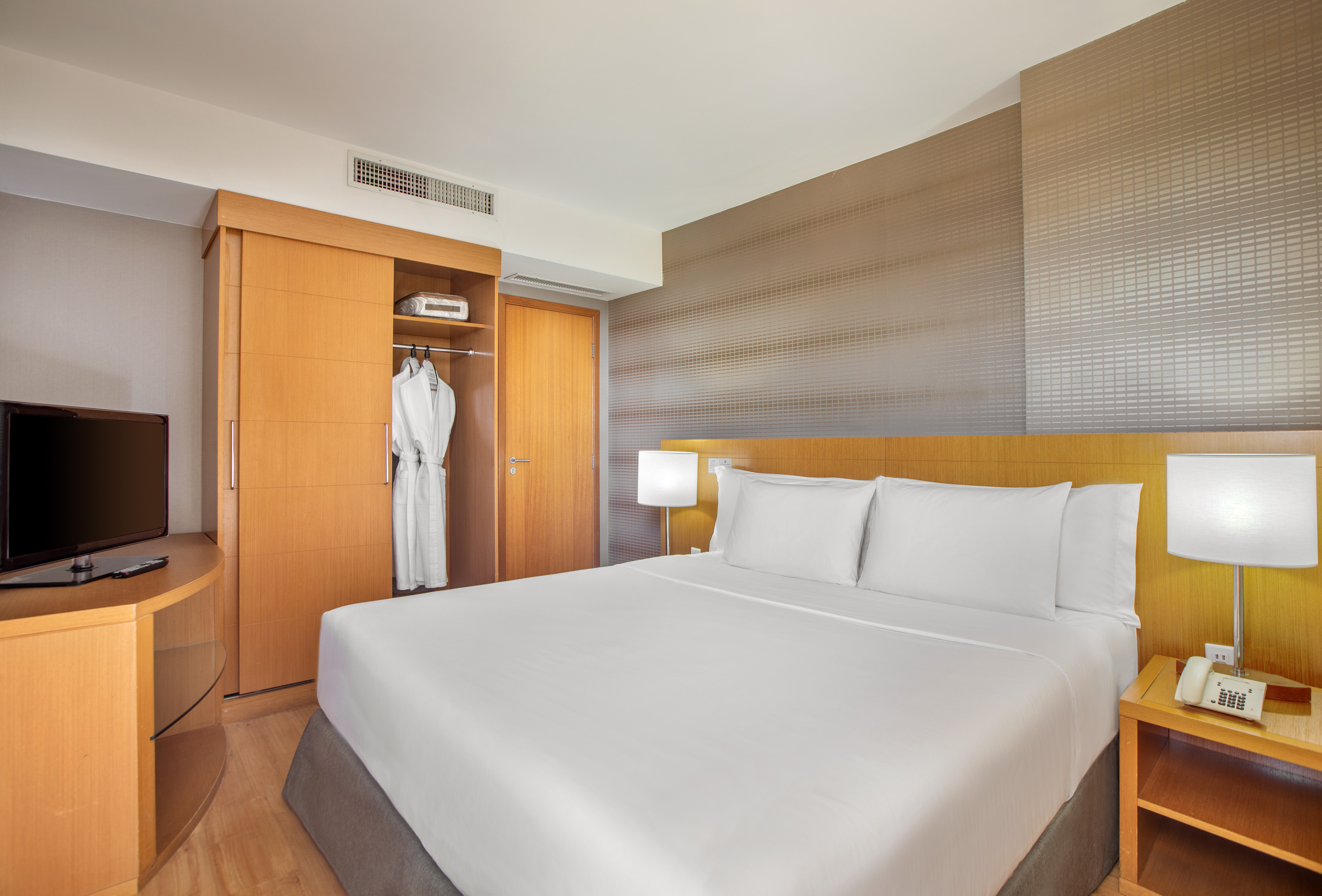 a bed with white sheets and a white robe in a room