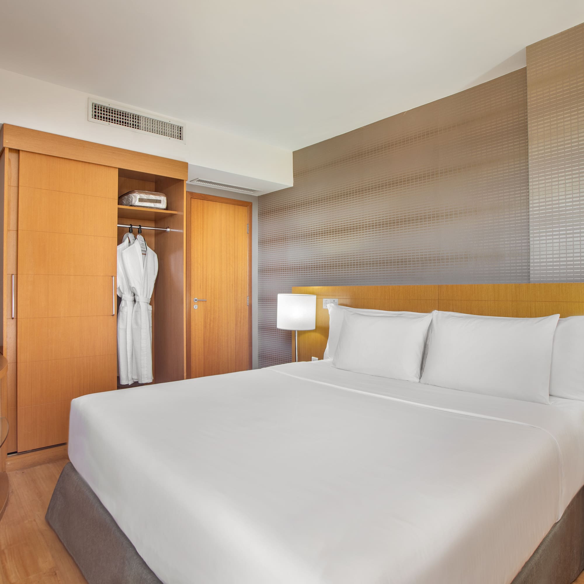 a bed with white sheets and a white robe in a room