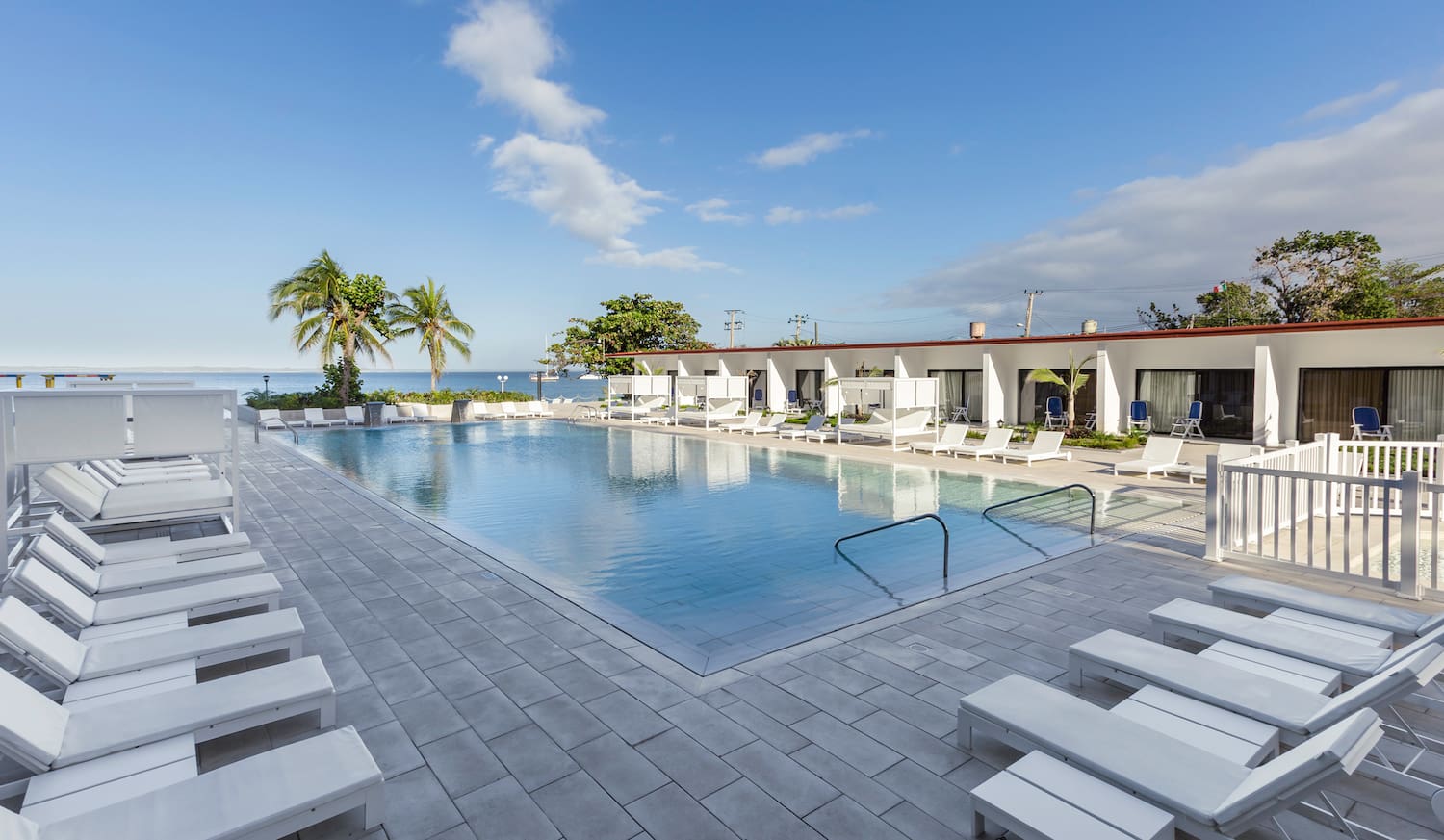 a pool with lounge chairs and a building with a body of water